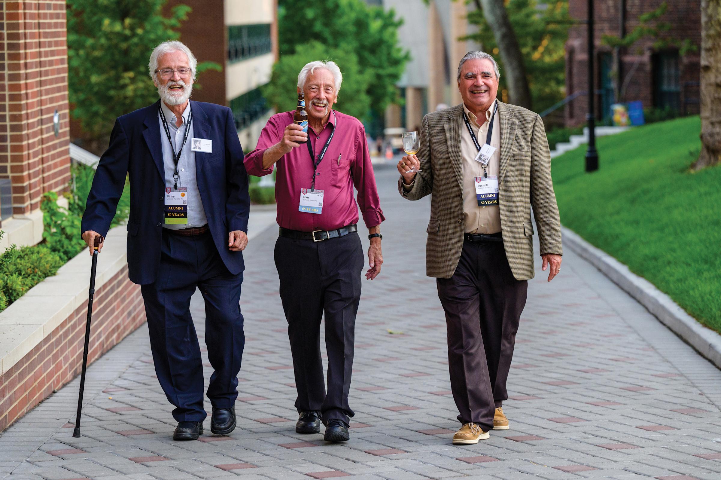 Three Stevens alumni smile for the camera as they walk up Whittpenn walk.