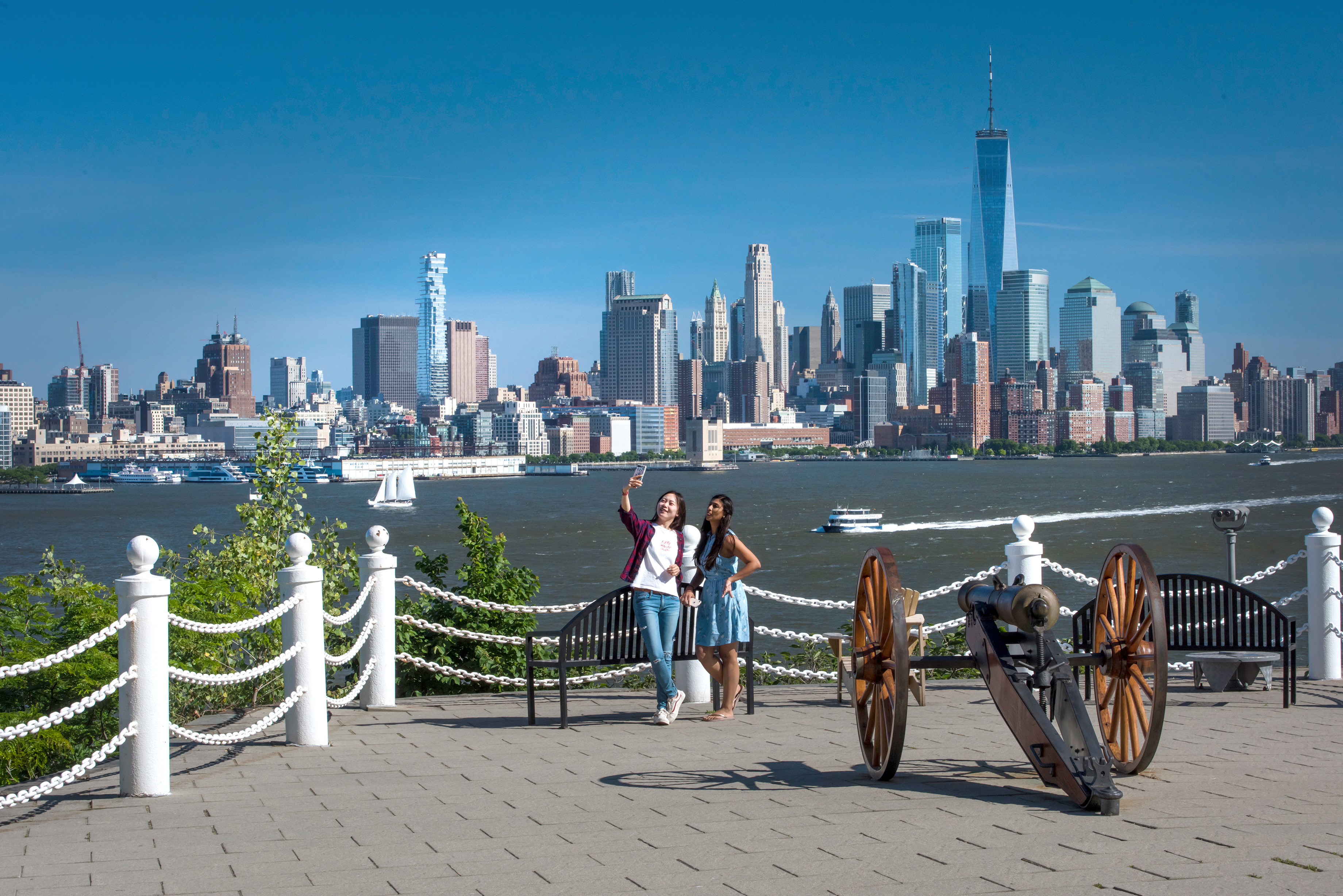 Two students pose for a selfie at Castle Point with a view of the New York Skyline.