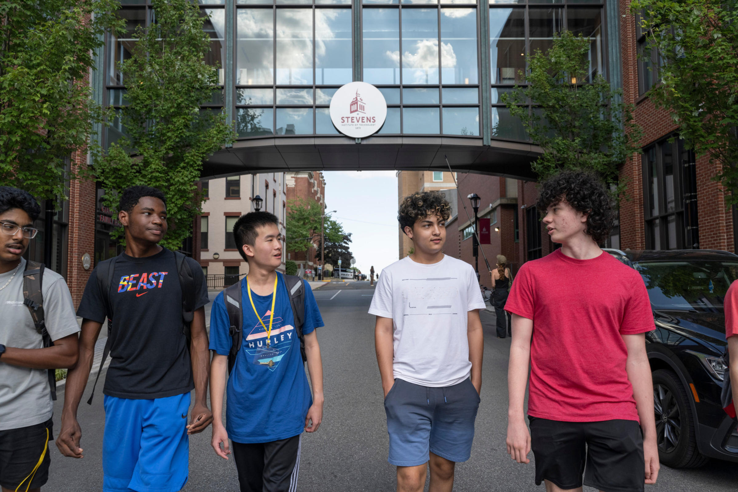 Several high school students walk and talk together on Stevens' campus.