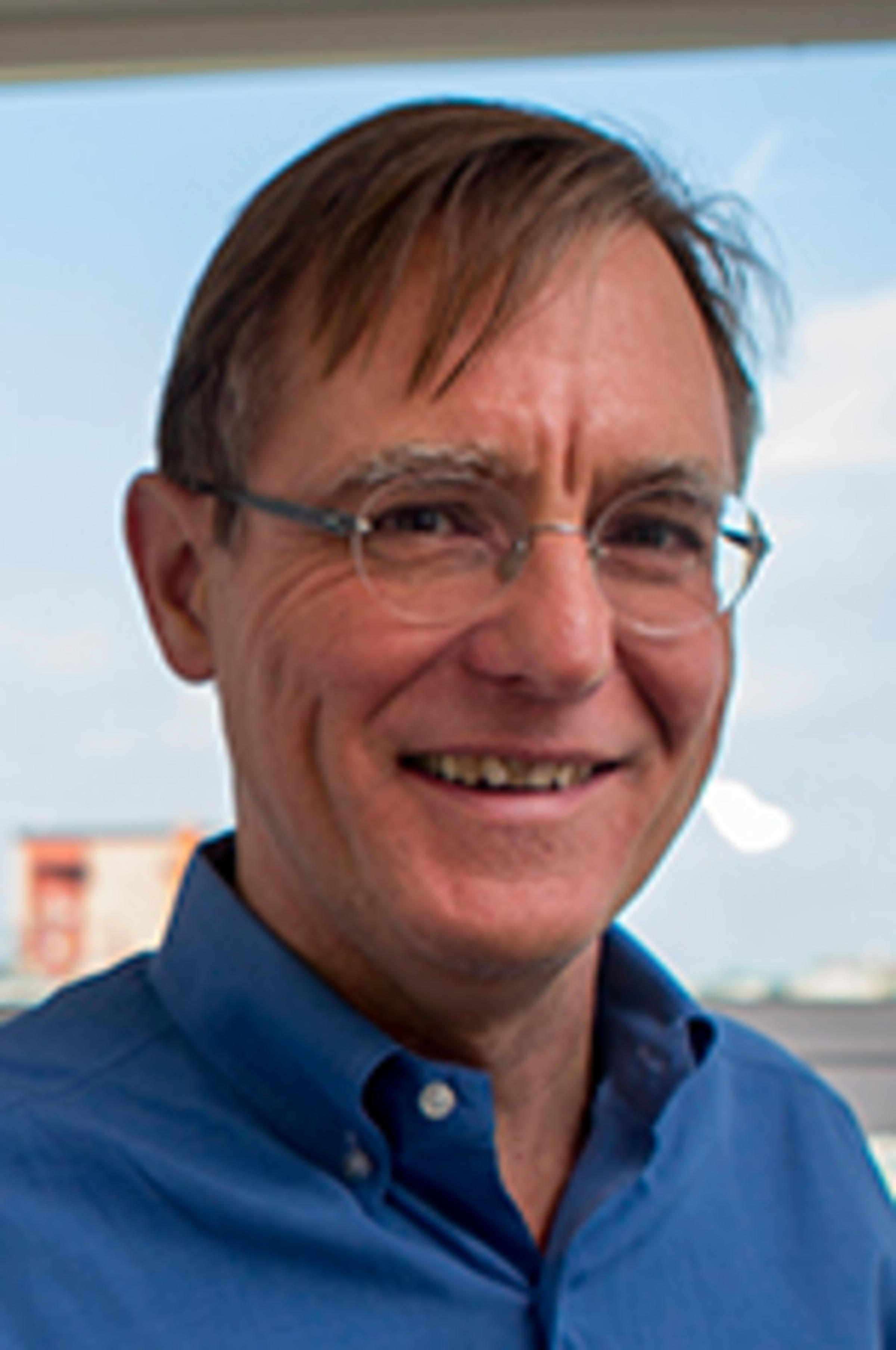 Headshot of Dr. Nickerson in a blue shirt with the Hoboken skyline in the background.