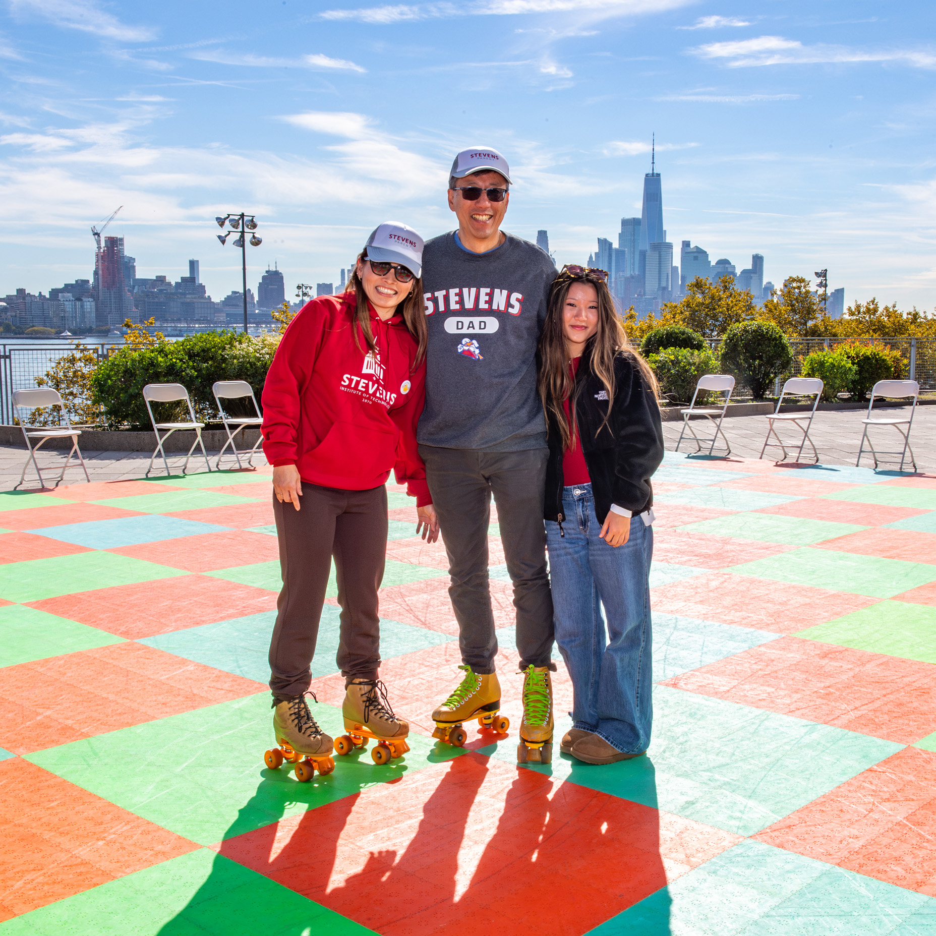 Family on rollerskates smiles to camera with New York City skyline in background.