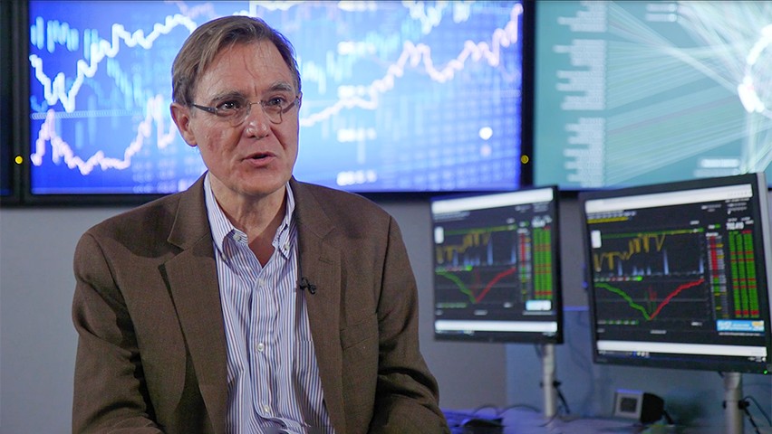 Dr. Jeffrey Nickerson sitting in front of several screens showing different data visualization graphs.