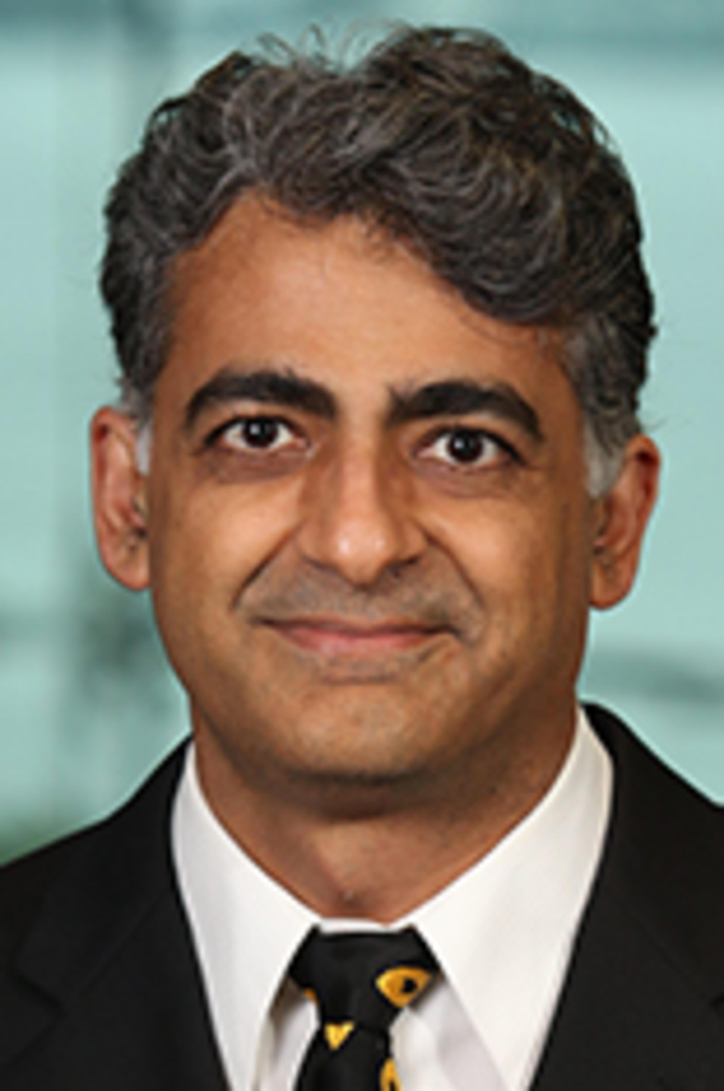 Headshot of Dr. Murad Mithani in a black jacket and dark tie with the New York City skyline in the background.