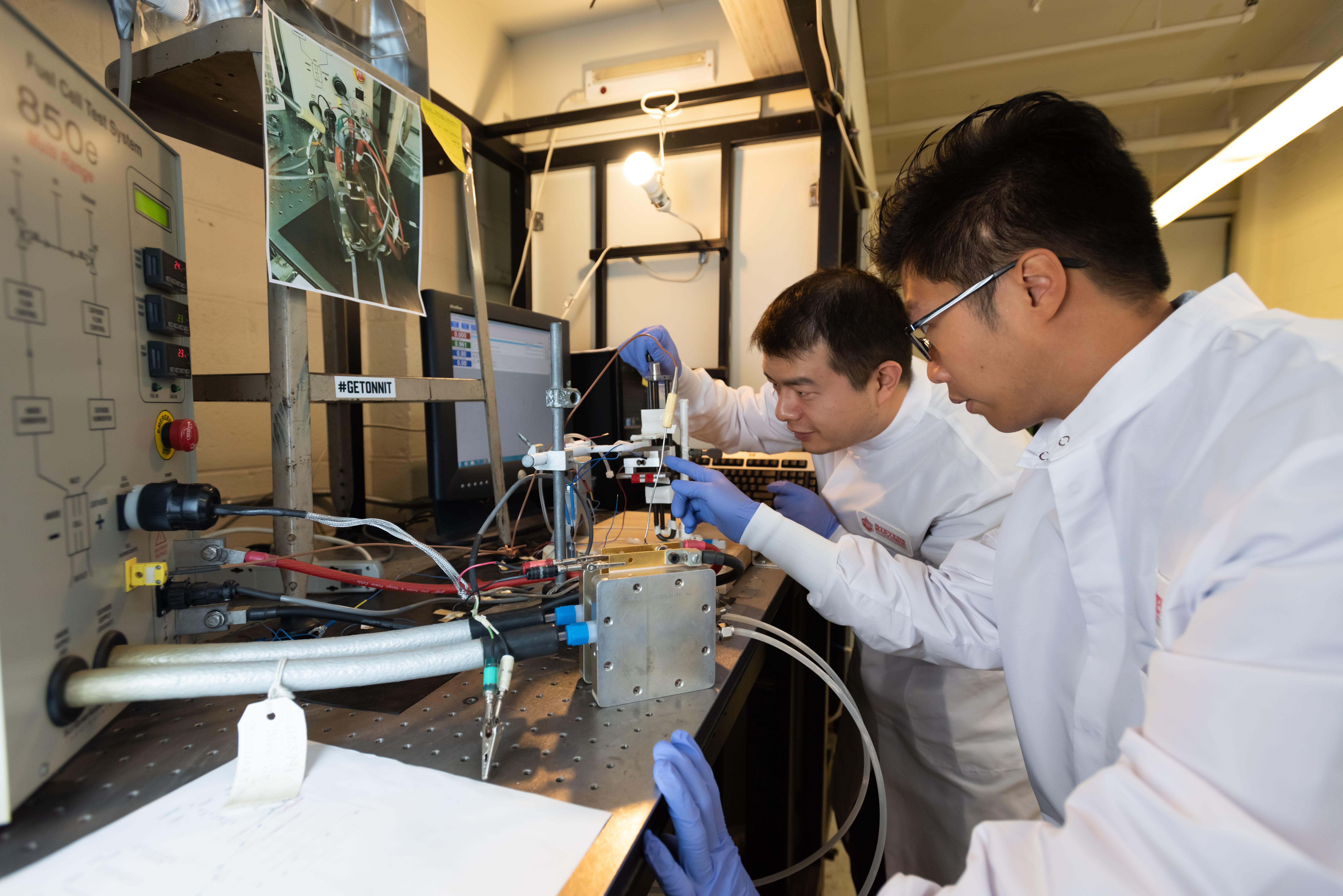 Two male students in a lab with protective gear performing a chemical experiment.