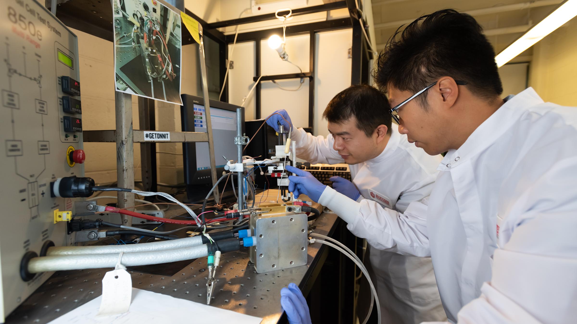 Two male students in a lab with protective gear performing a chemical experiment.