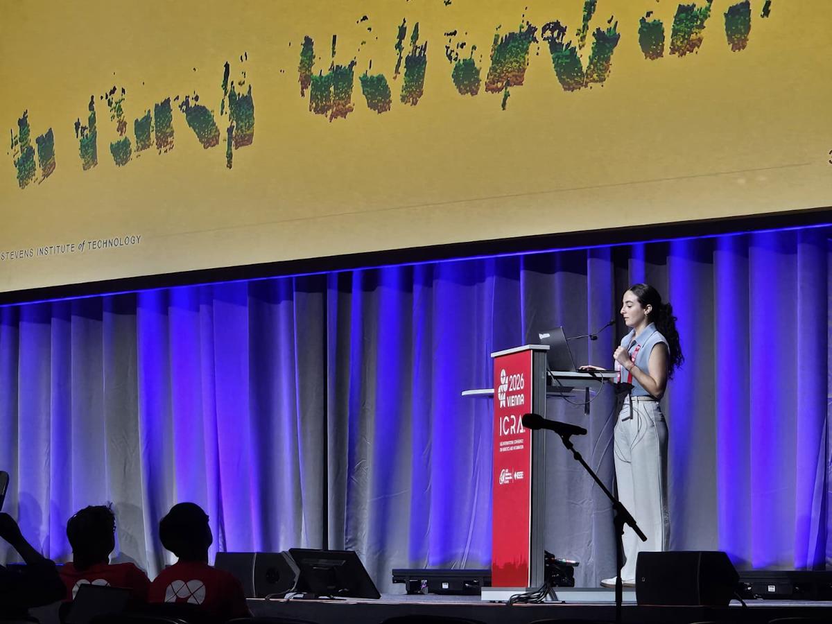 A photograph of Ivana Collado Gonzalez standing at a podium to present at a robotics conference.