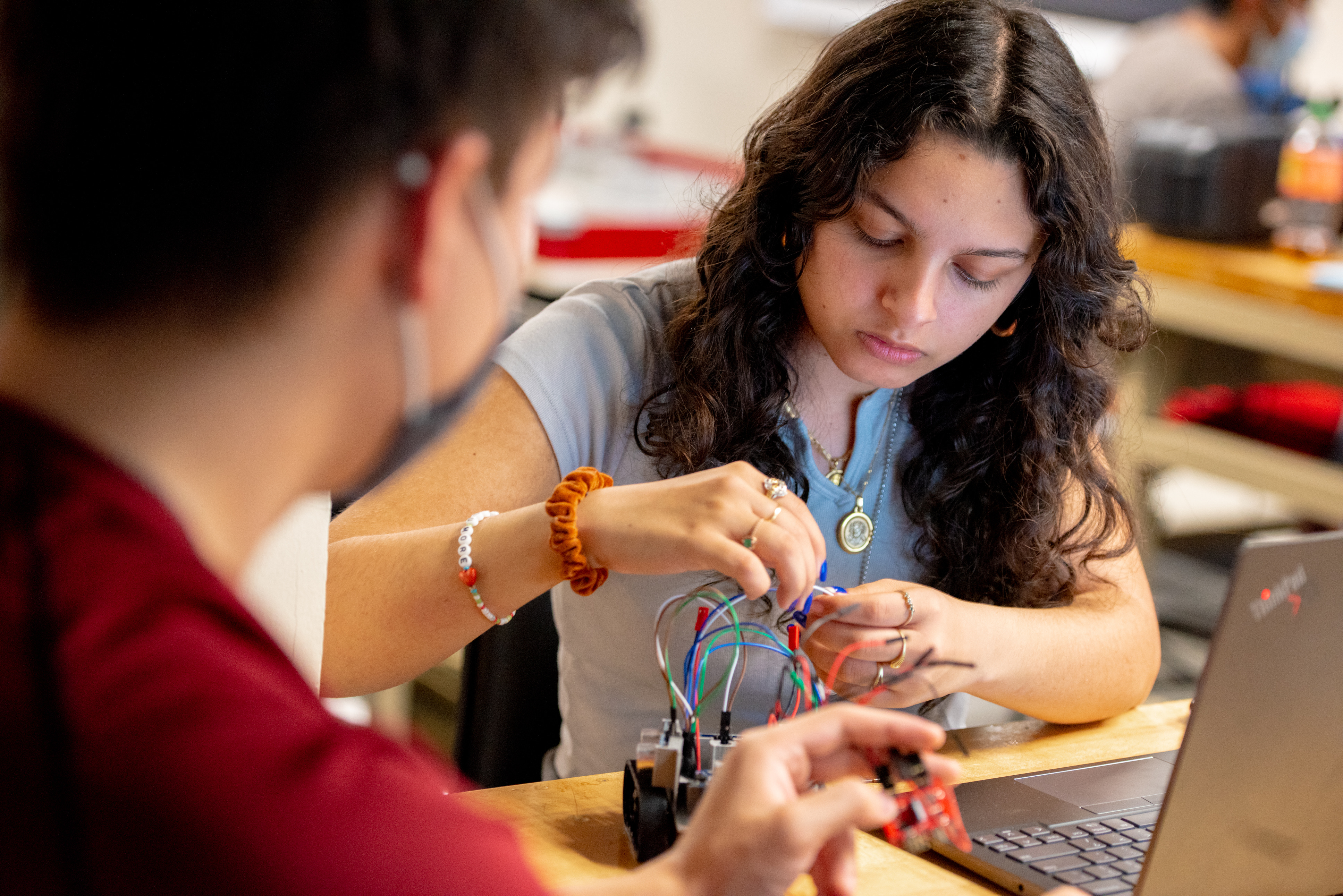 A student working with wires on a robotics project.
