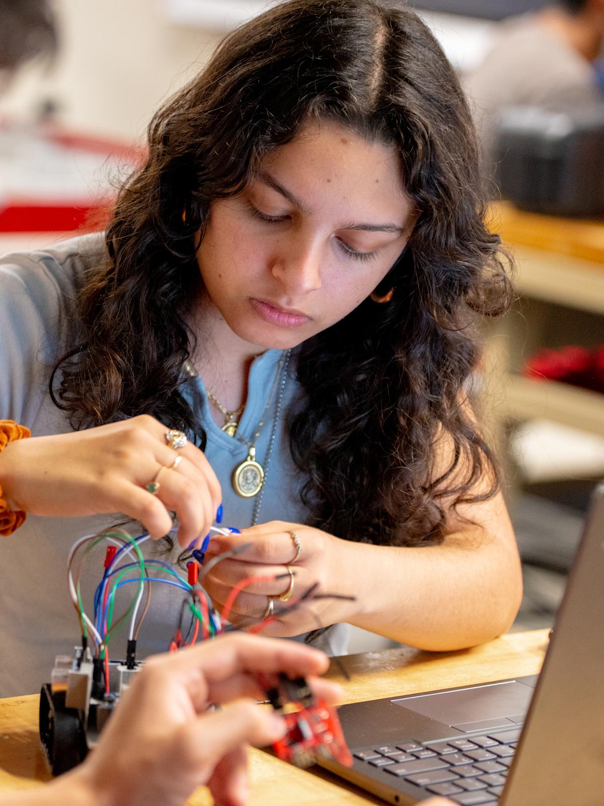 A student working with wires on a robotics project.