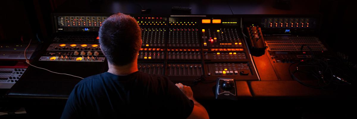 Three students sitting at a sound board in the music studio.
