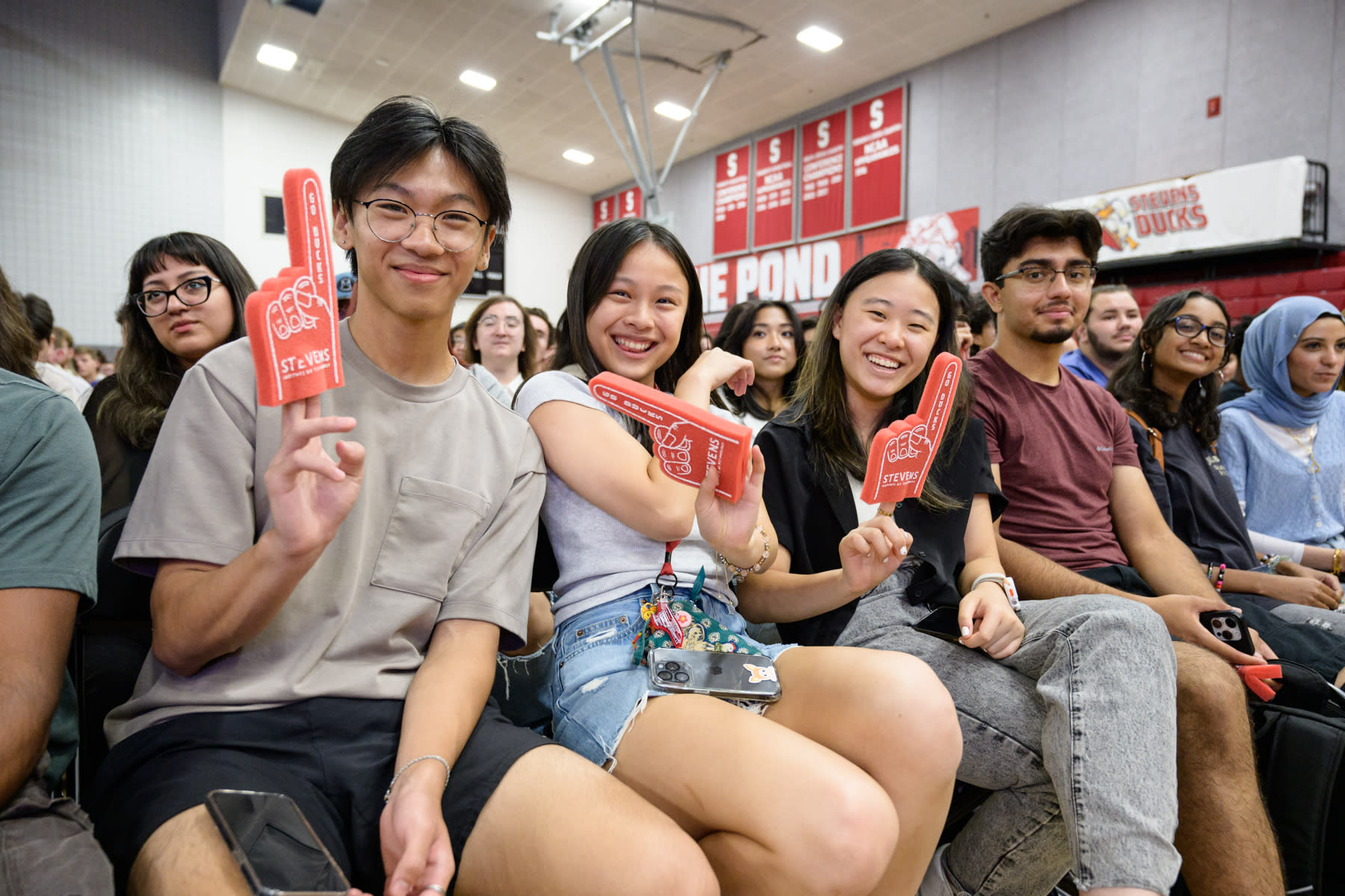 Students pose with red foam fingers at an Orientation event in Canavan Arena.