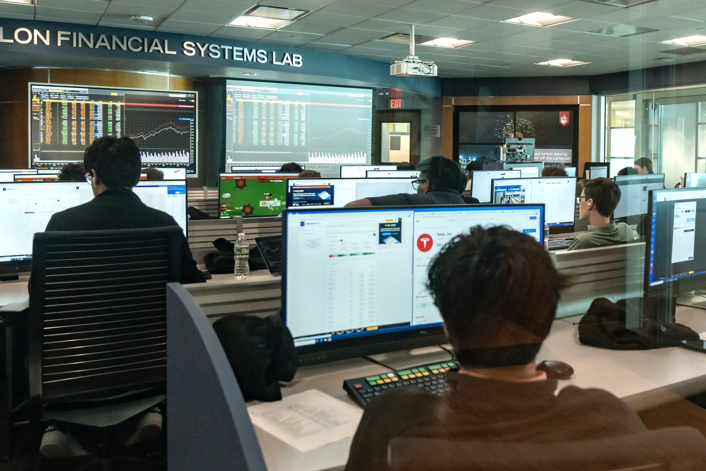 A group of students sit in front of computer terminals in the Hanlon Financial Systems Lab