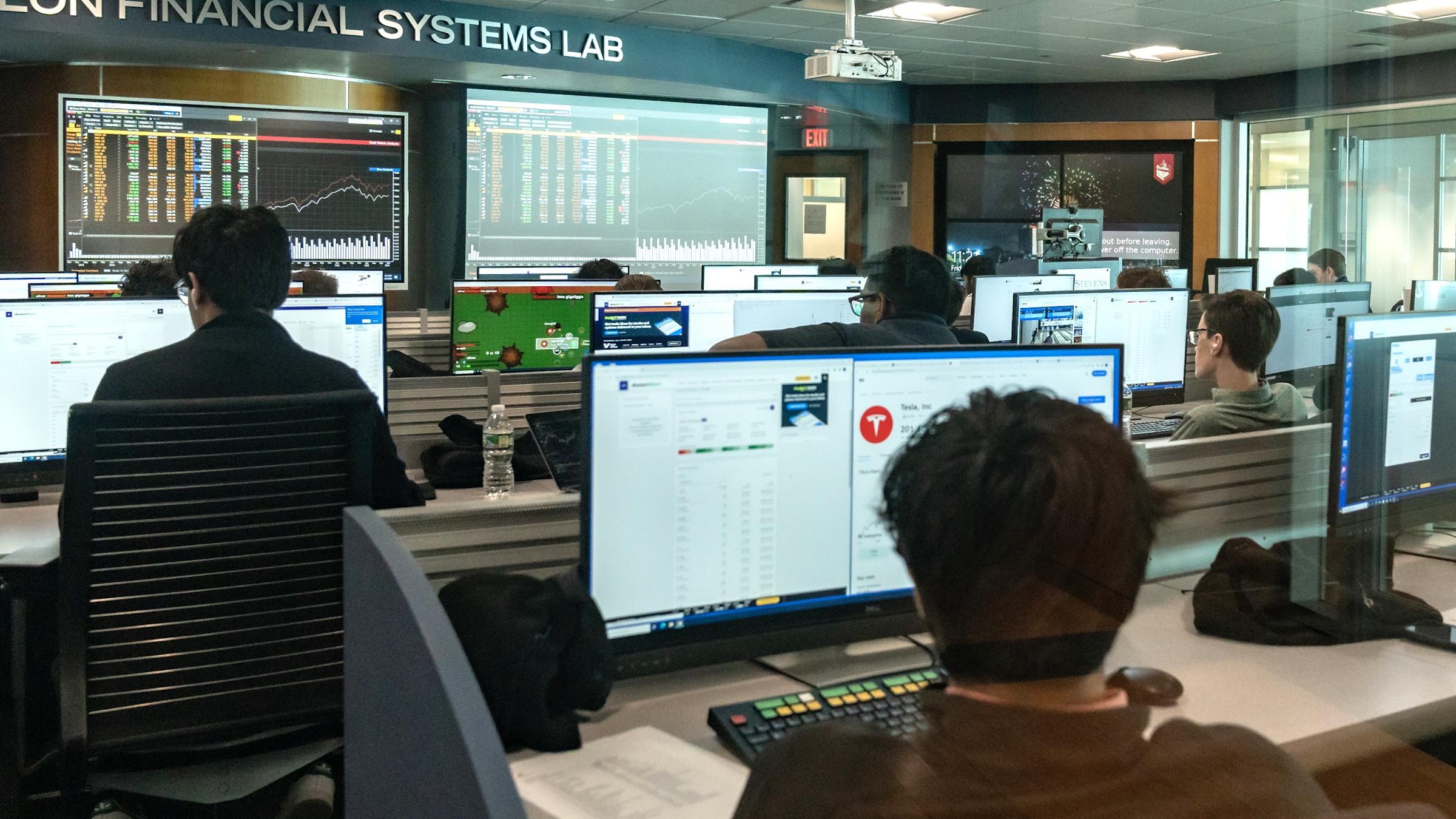 A group of students sit in front of computer terminals in the Hanlon Financial Systems Lab