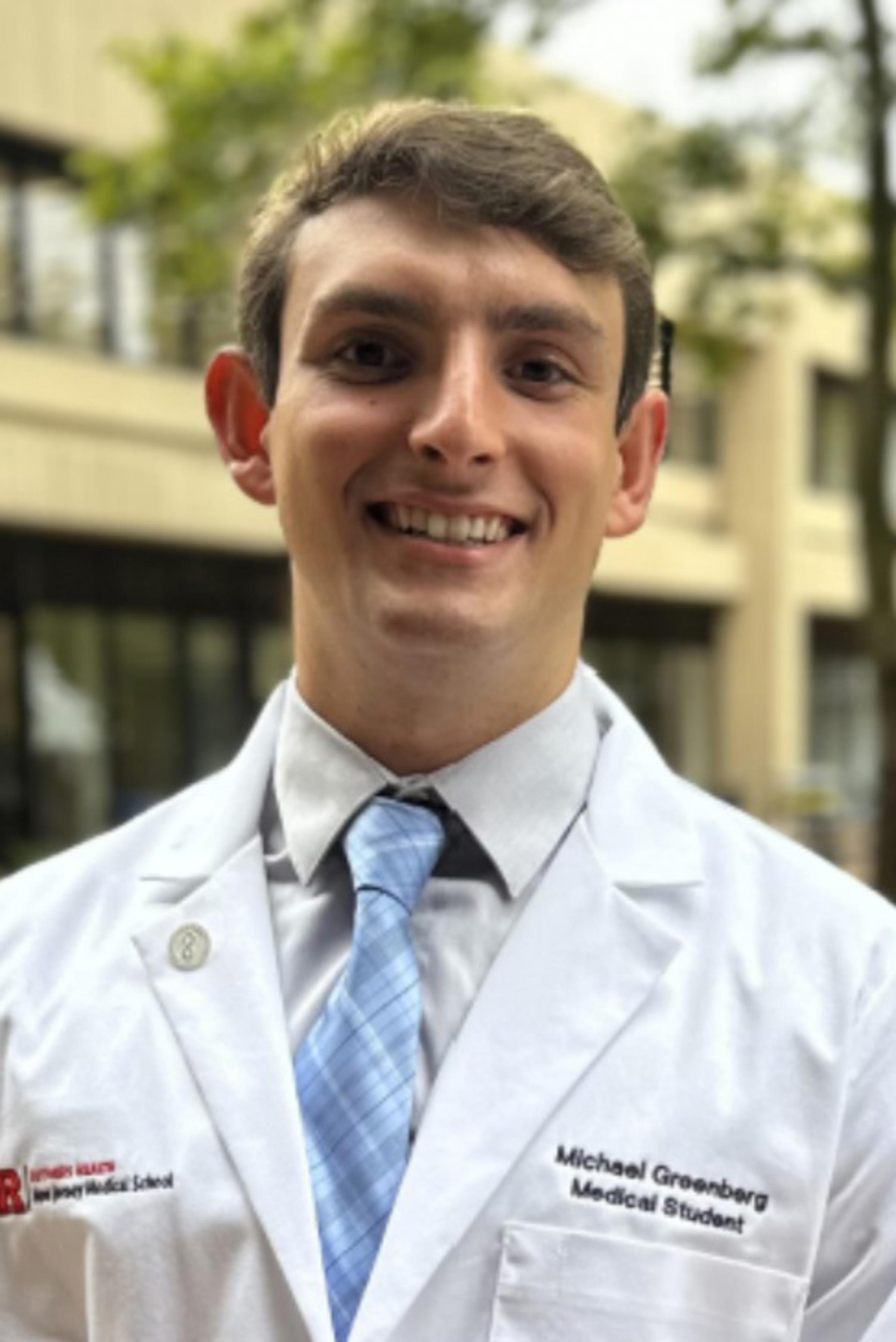 Stevens graduate Michael Greenberg wearing a white lab coat.