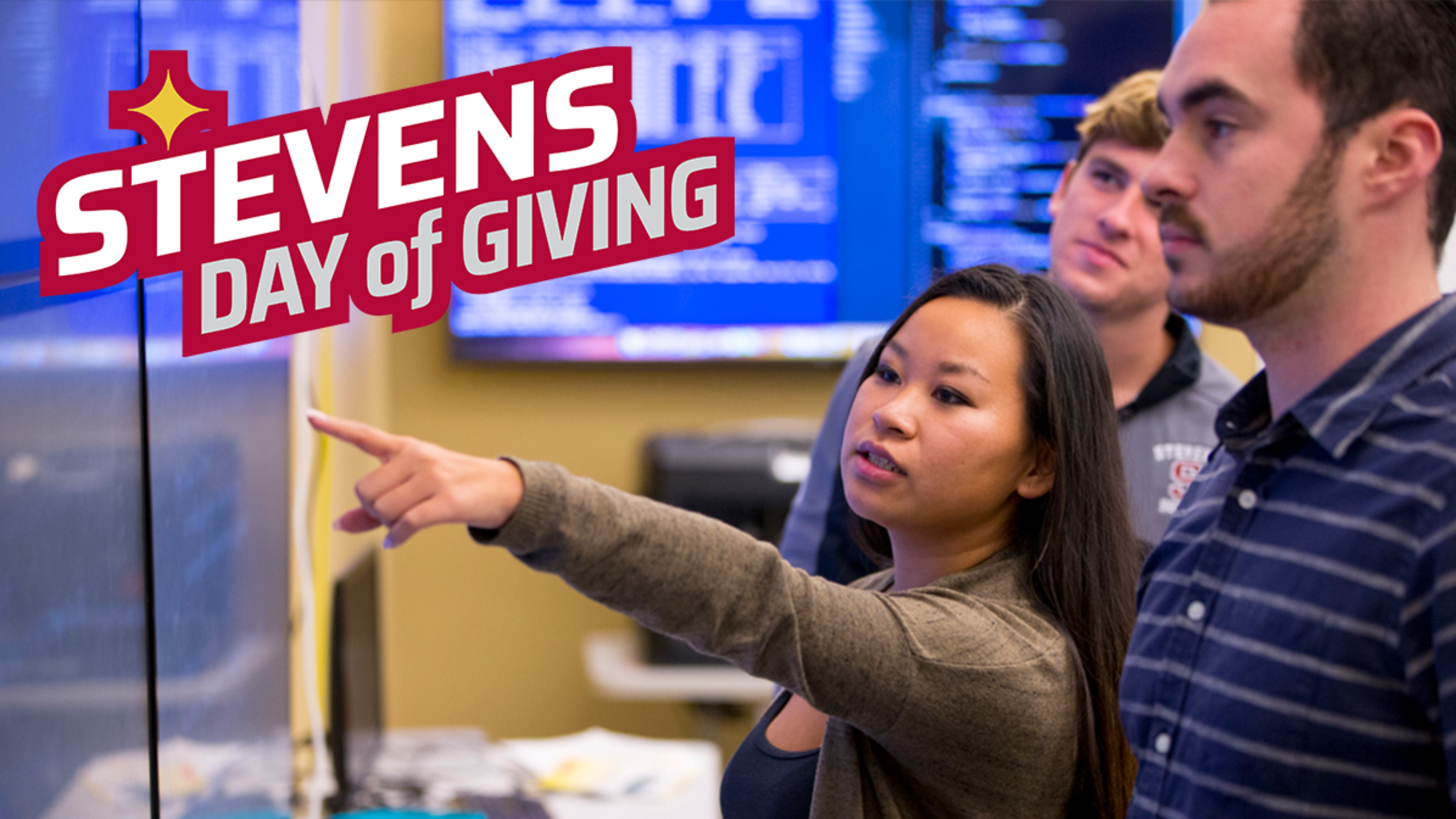 A group of students observe digital screen displaying financial data as one student points out some of the information.