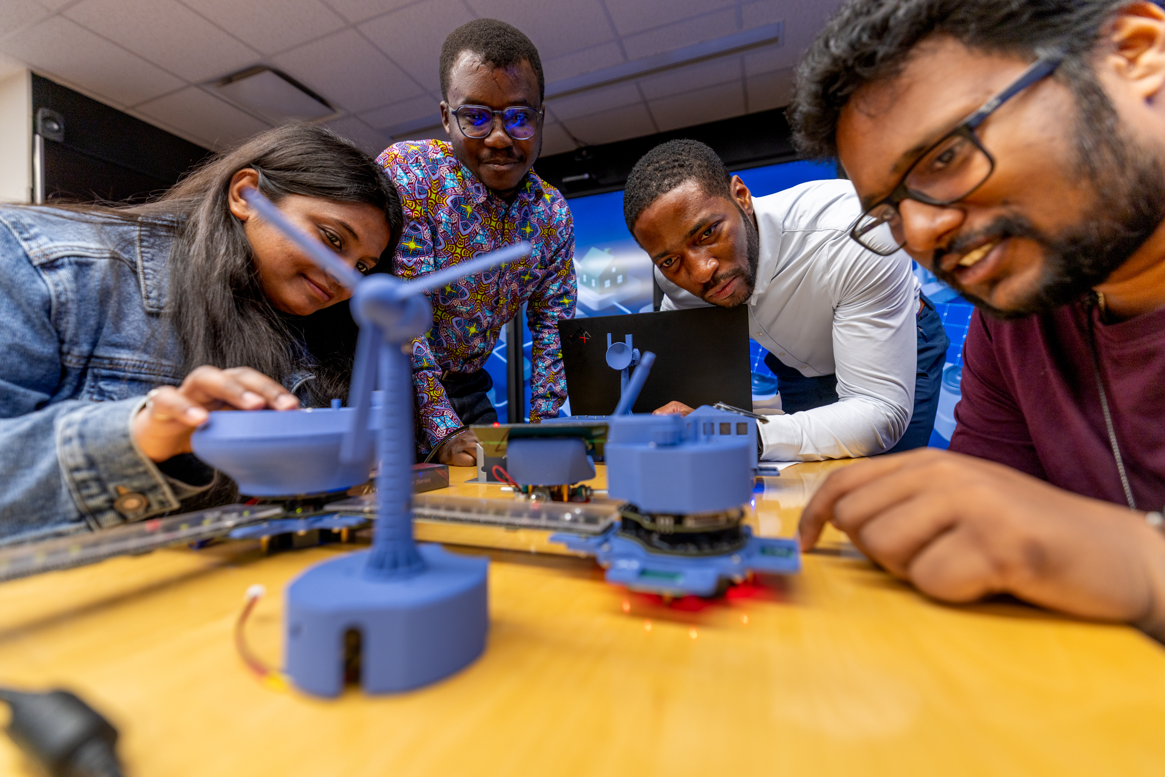 A female student, two male students and a professor looking at an experiment.