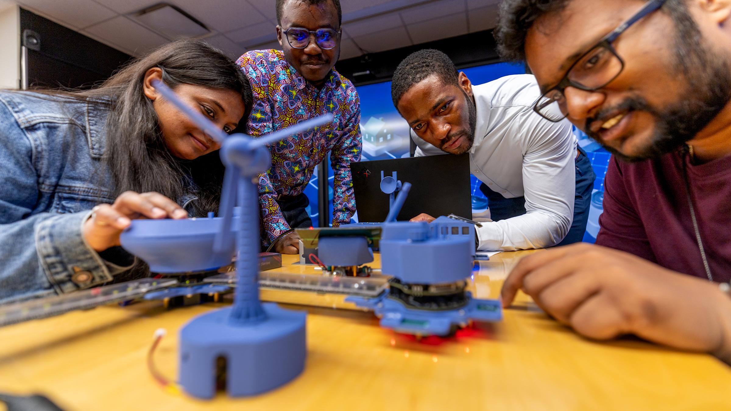 A female student, two male students and a professor looking at an experiment.