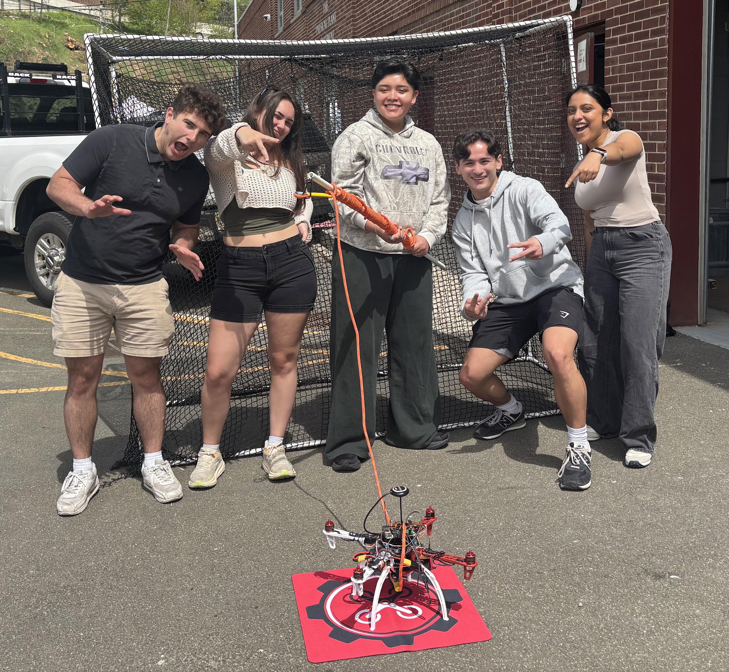 Team members George Redfern, Gianna Cerbone, Camila Valdez, Thomas Ung and Spurthi Setty stand in front of a drone cage with their QuackOps drone prototype.