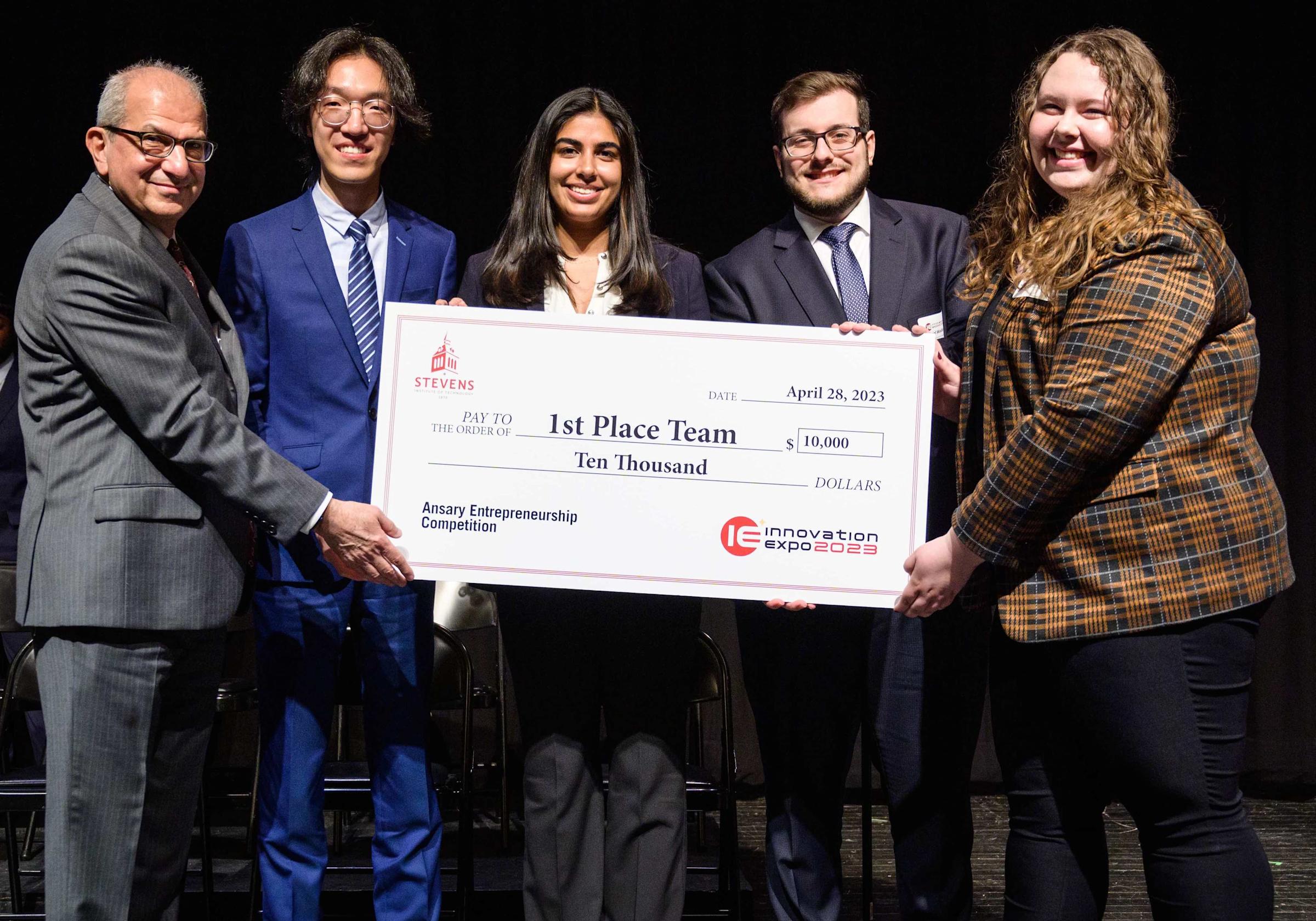 Winning team at Stevens pitch competition accepting oversized $10,000 check from President Nariman Farvardin