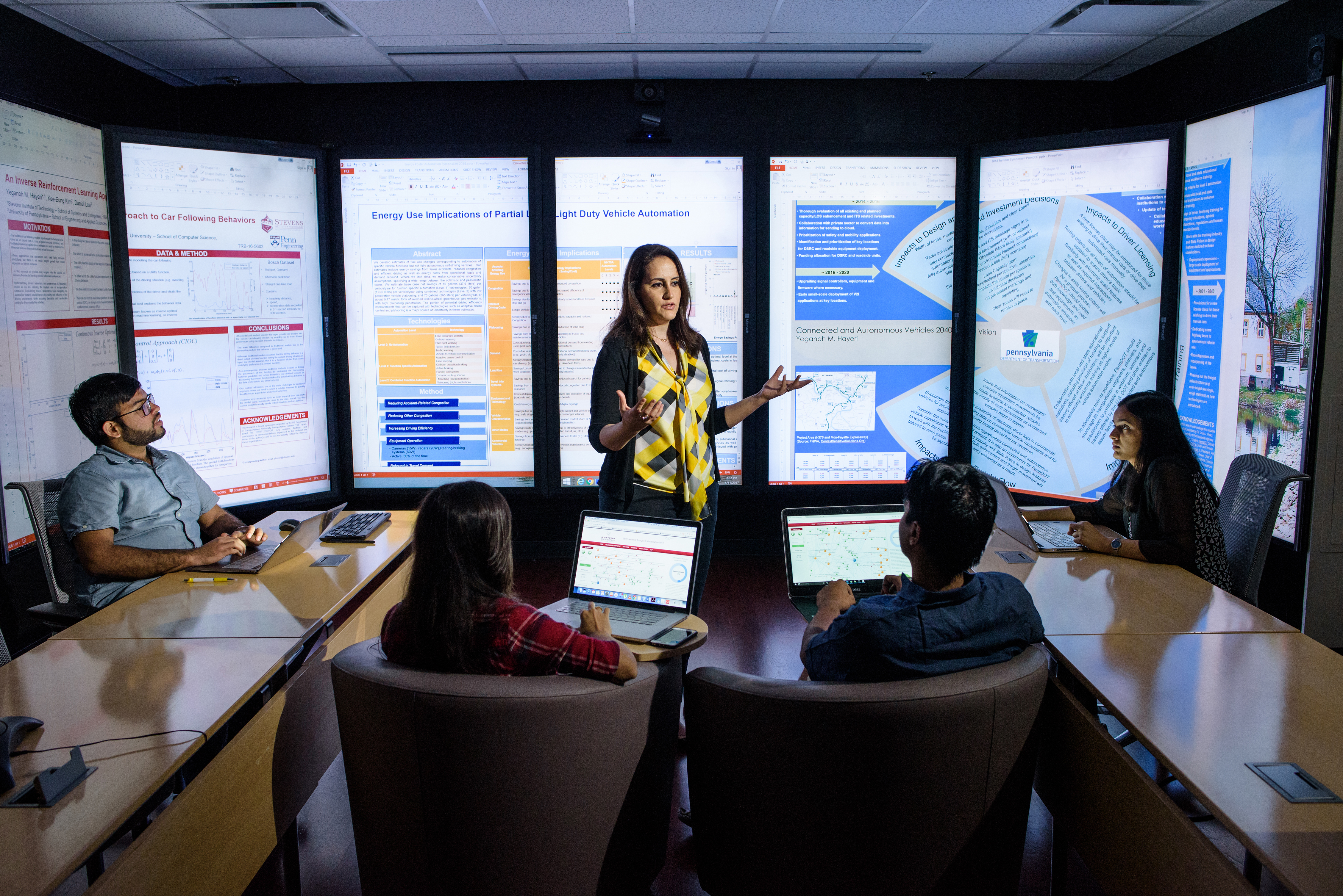 Instructor teaches small class in front of immersion wall of data