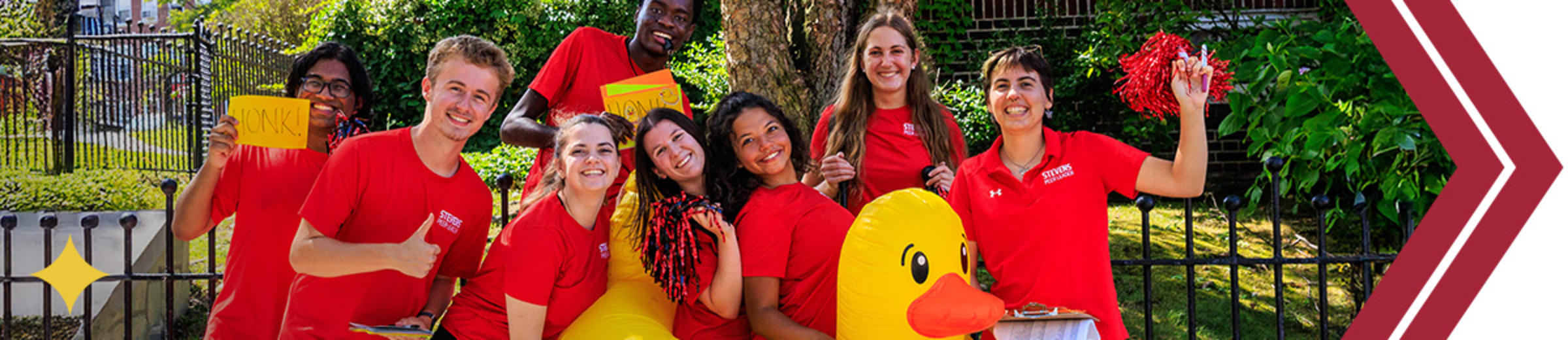 Group of students wearing red t shirts and an inflatable duck smiling to camera.
