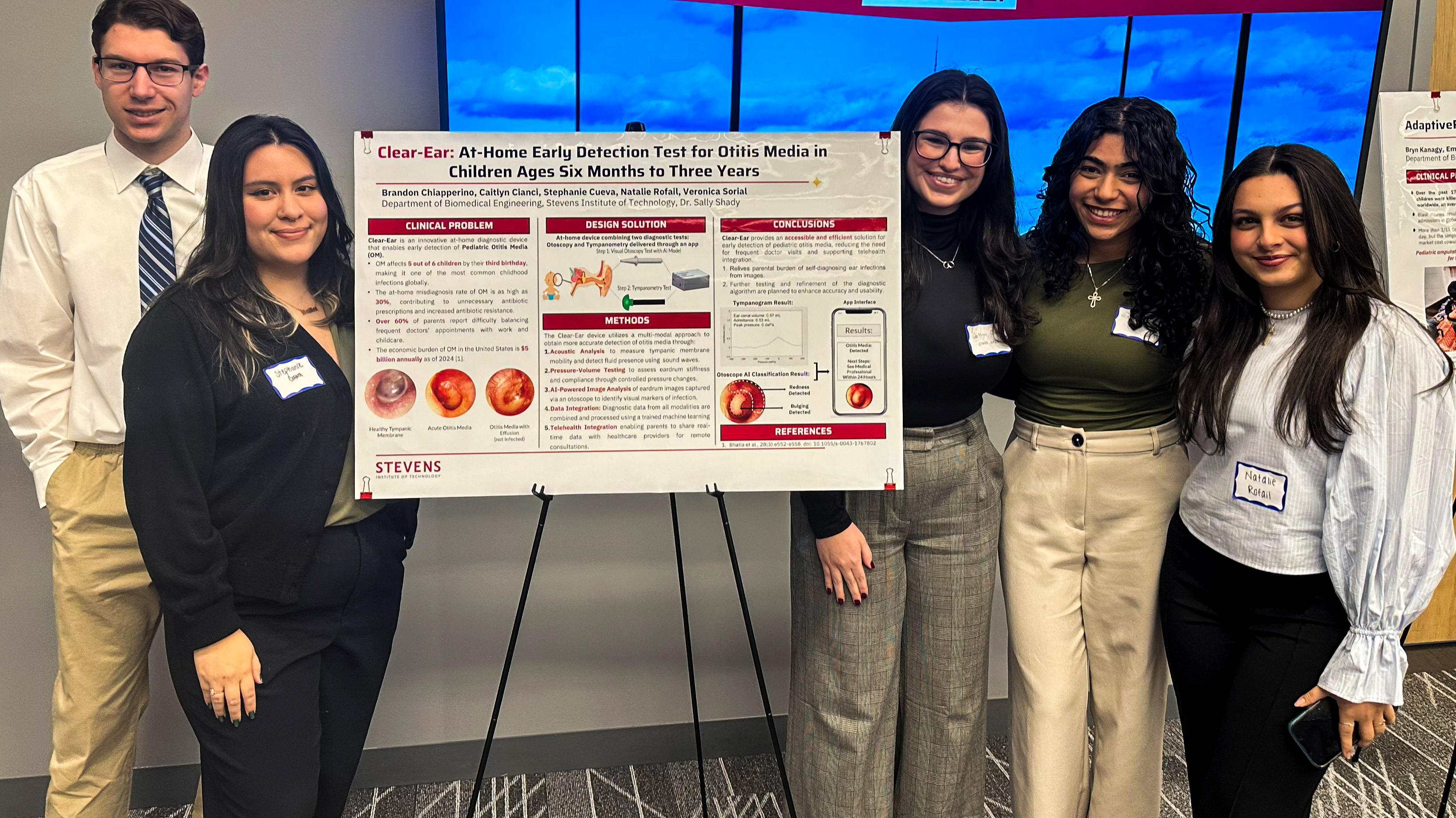 Five Stevens students surround a poster board presentation, with two students on the left and three on the right.