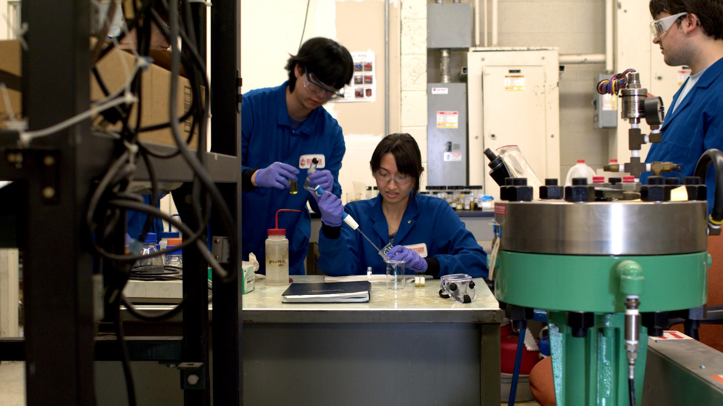 Three students in a lab conducting an experiment.