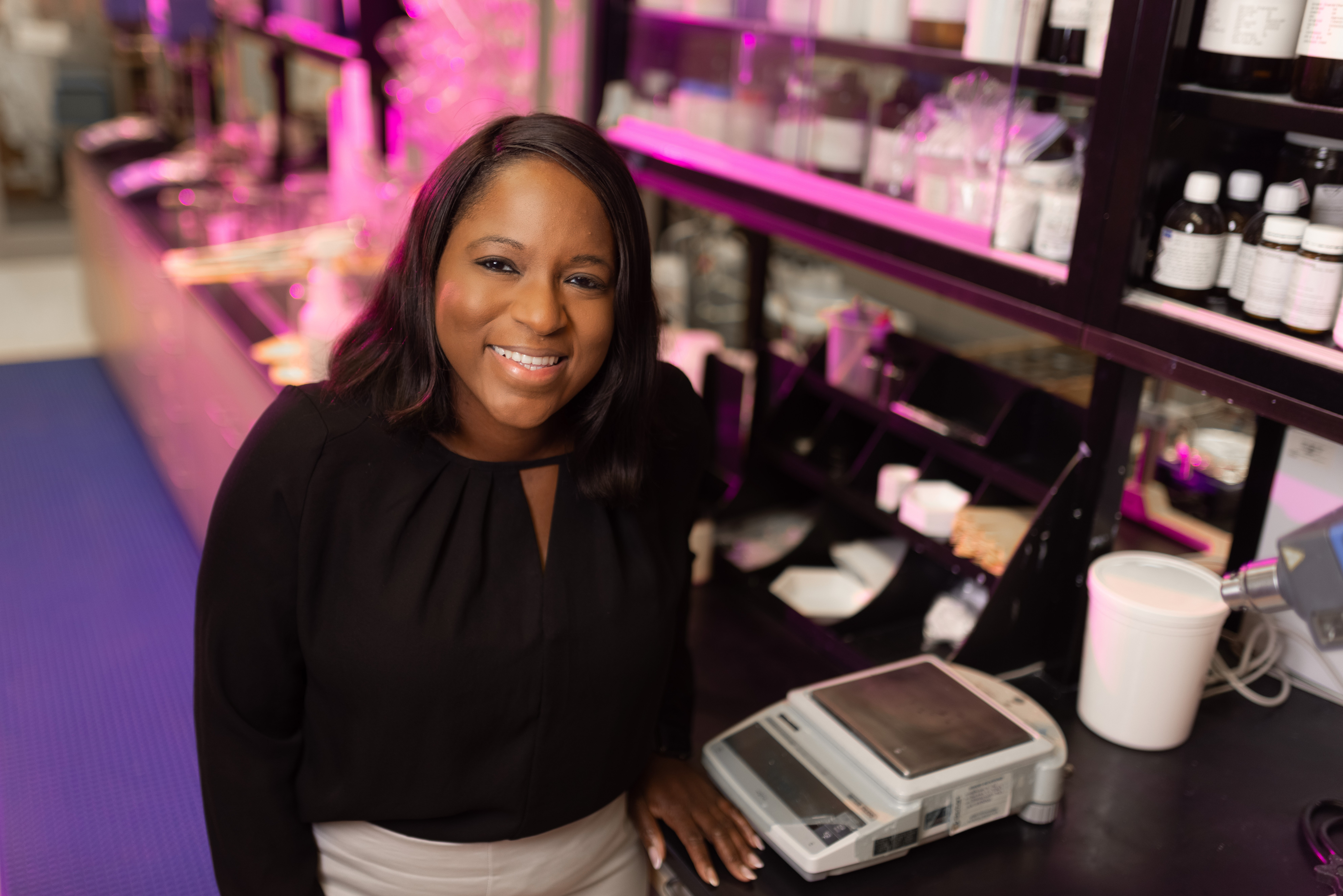 Sabrina Henry in a lab with shelves of bottles behind her.
