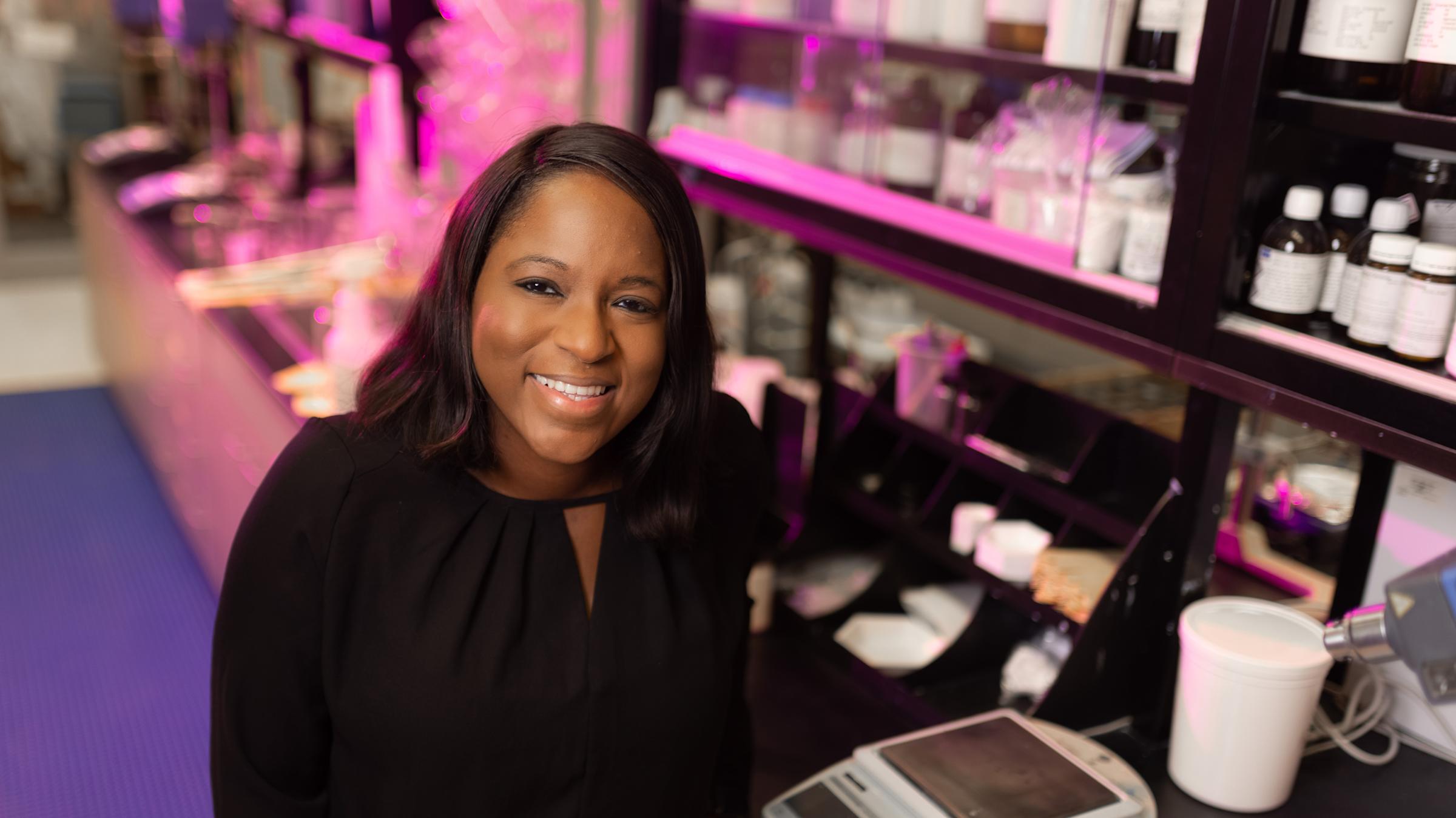 Sabrina Henry in a lab with shelves of bottles behind her.