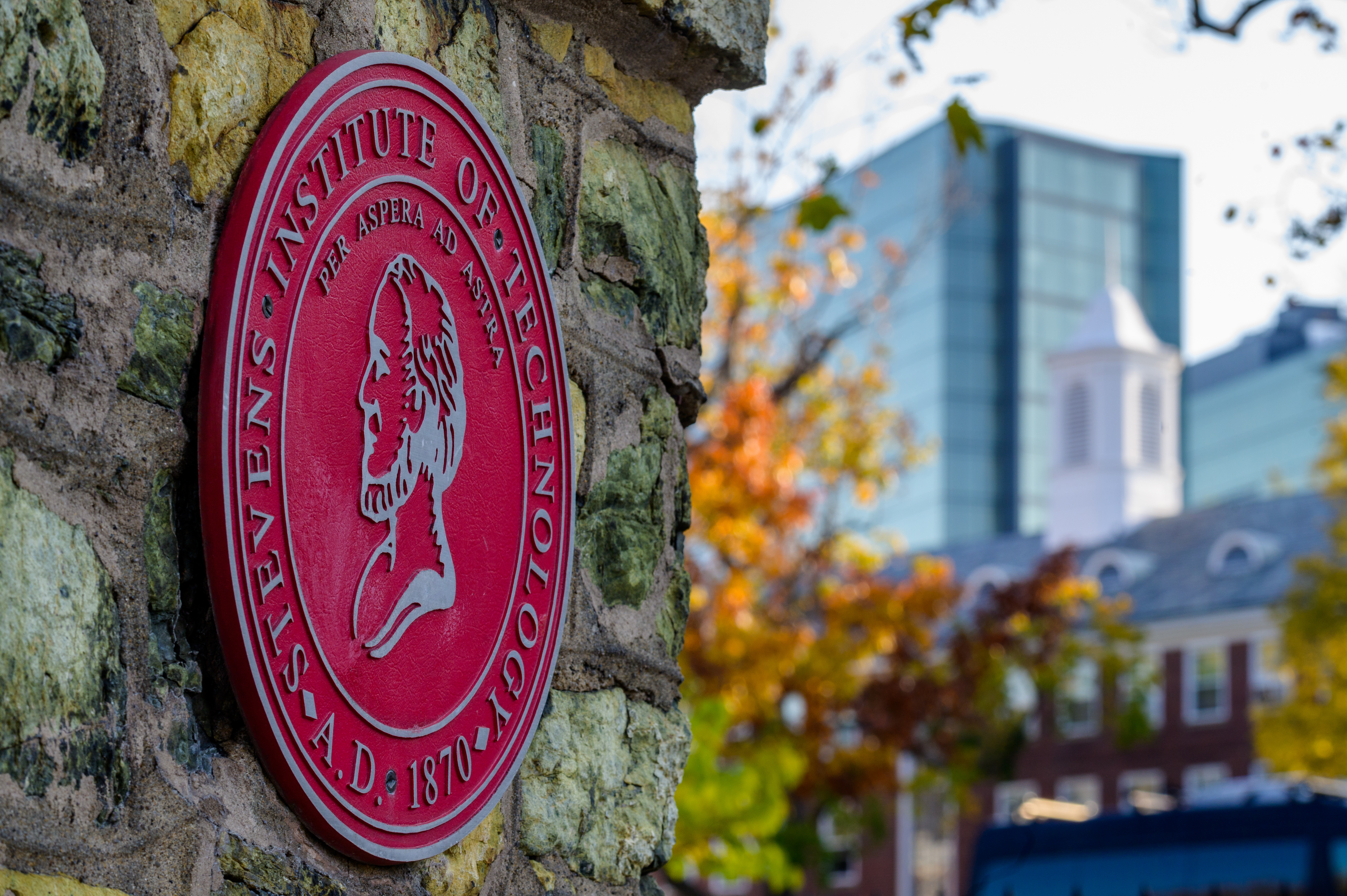 Stevens seal on entrance gate with campus in background
