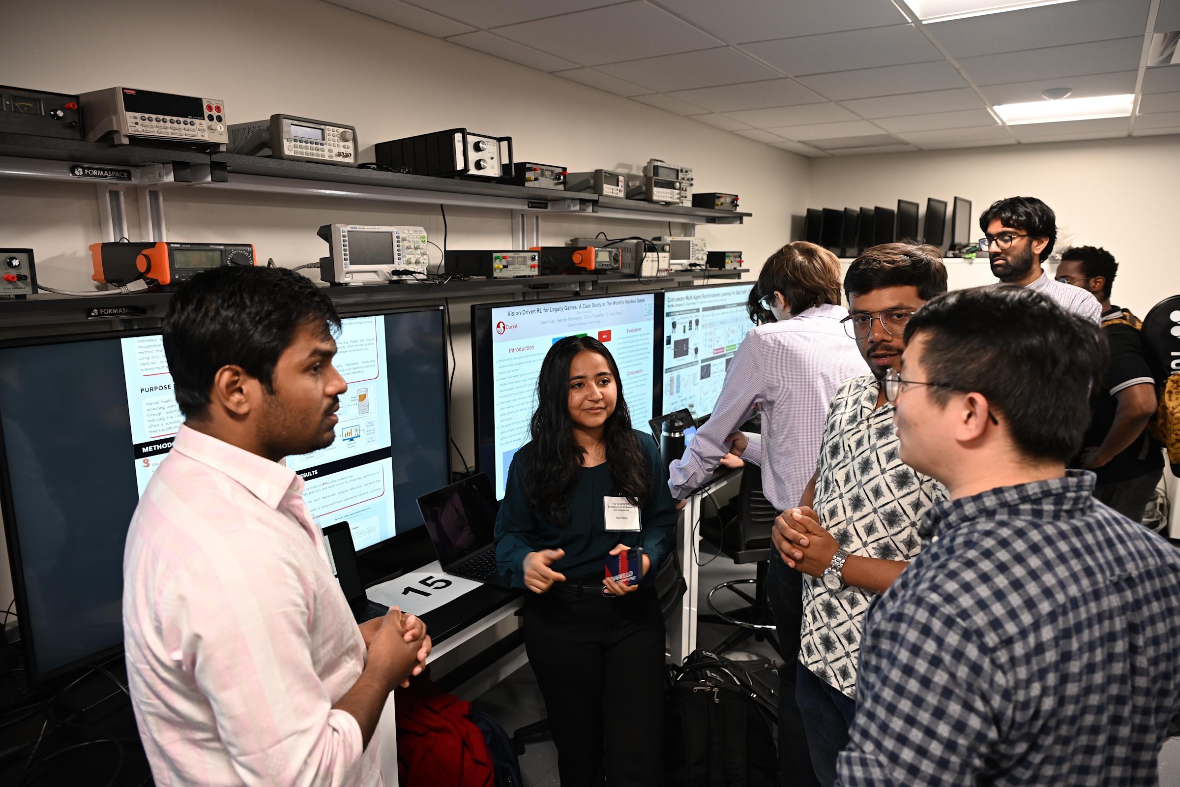 A group of four people stand in a group talking with posters behind them.