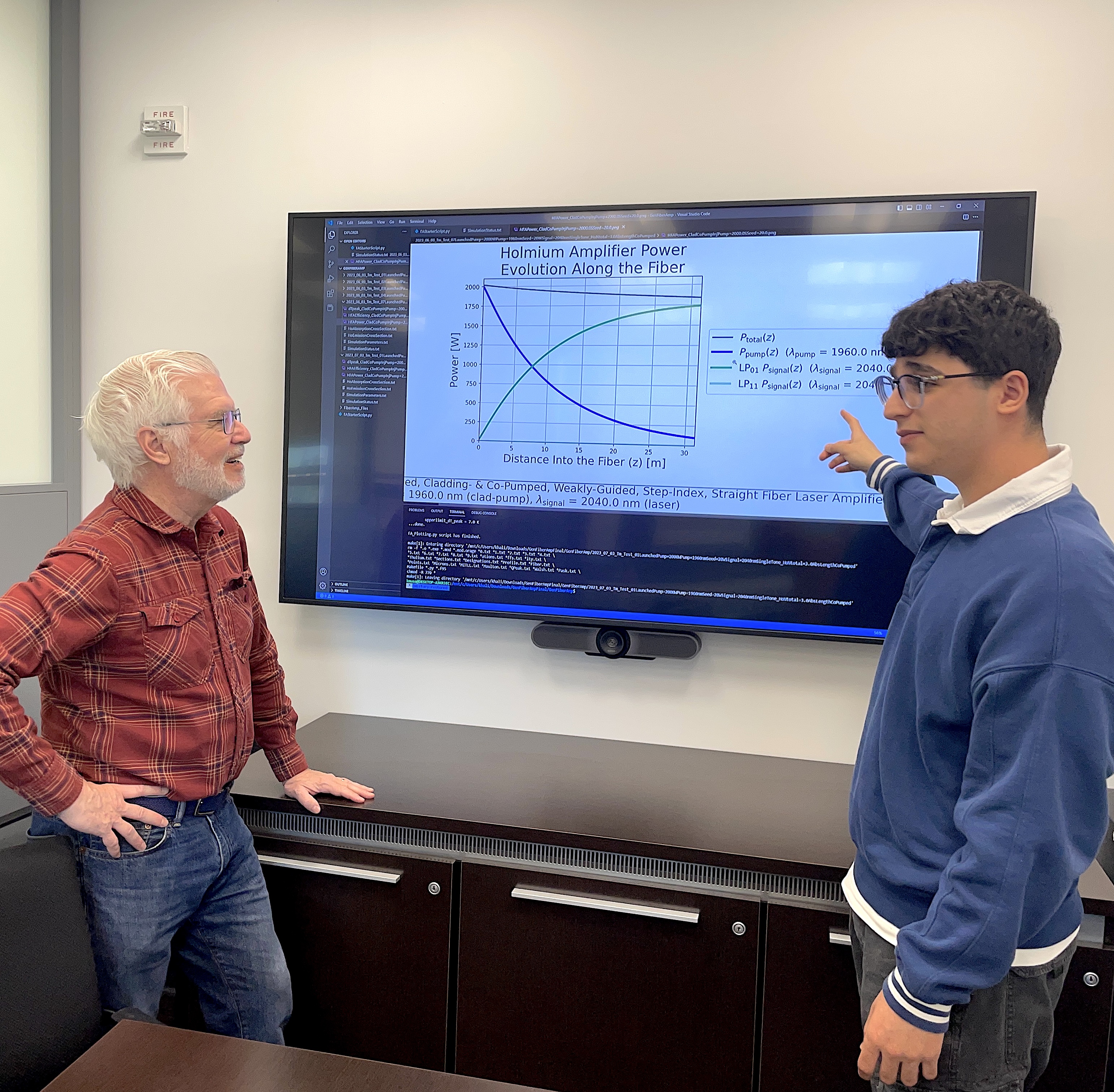 A photo of Ed Whittaker and Khalid Musa talking in front of a big screen with physics equations