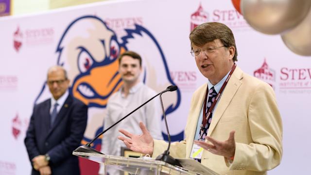 Kevin Ryan speaks at podium with President Nariman Farvardin in the background