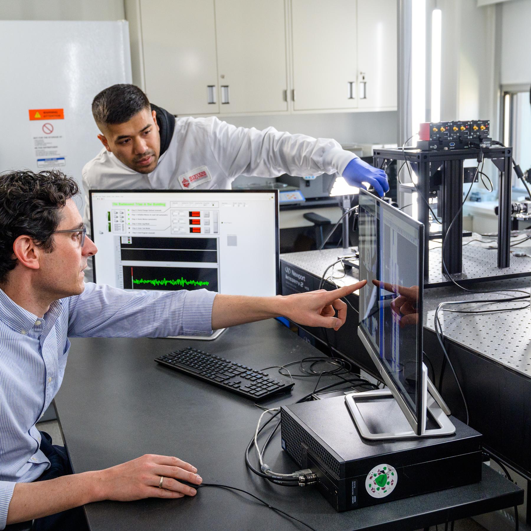A professor and research assistant view findings on a computer.