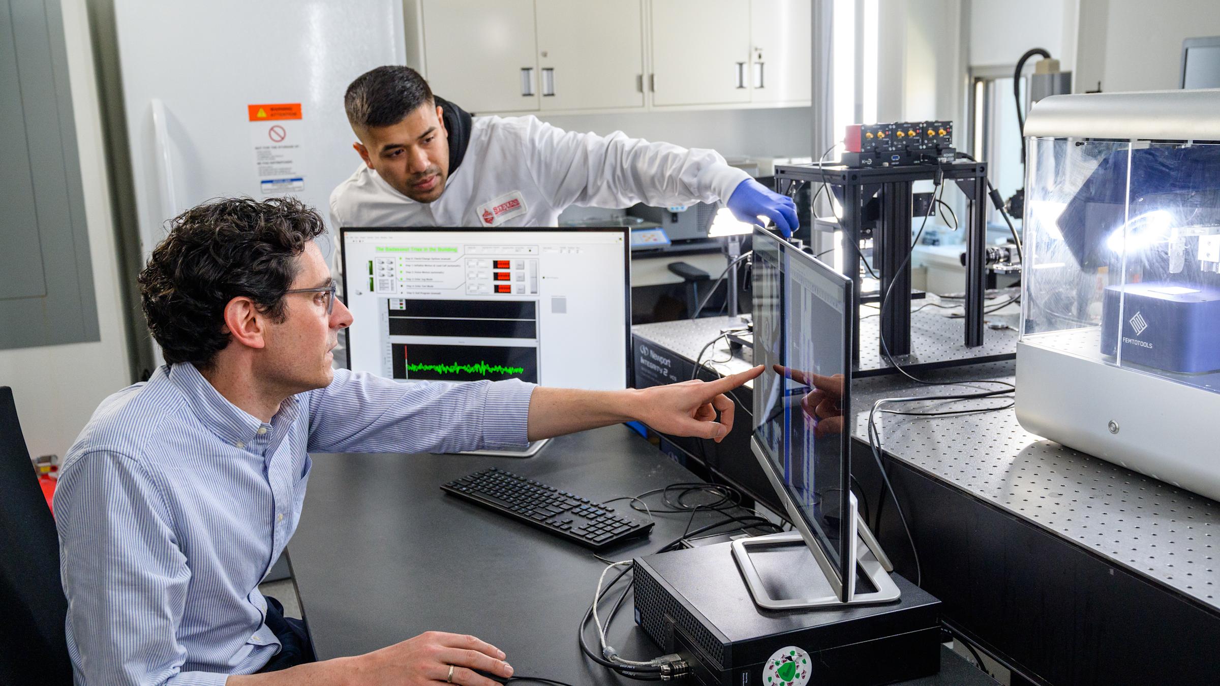 A professor and research assistant view findings on a computer.