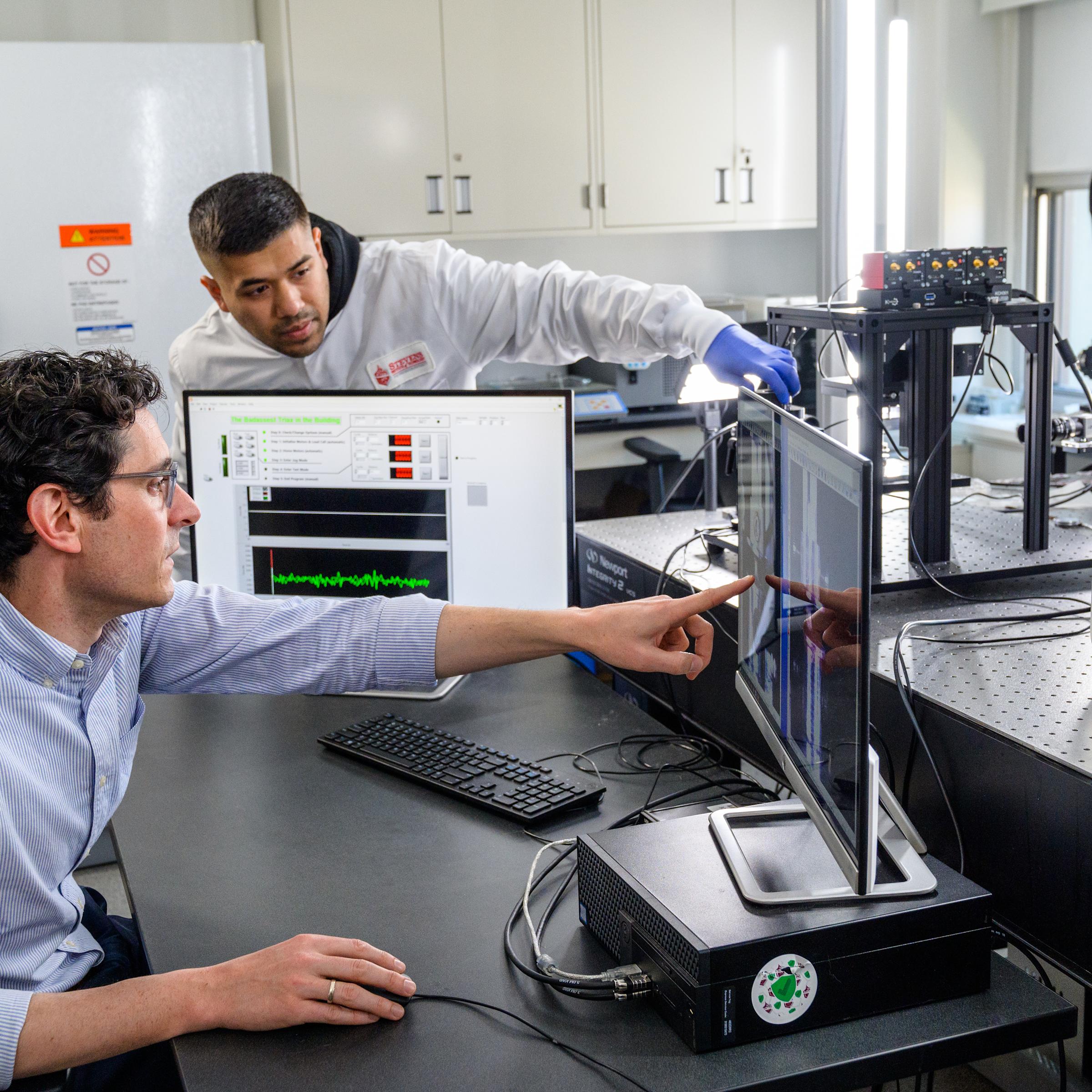 A professor and research assistant view findings on a computer.