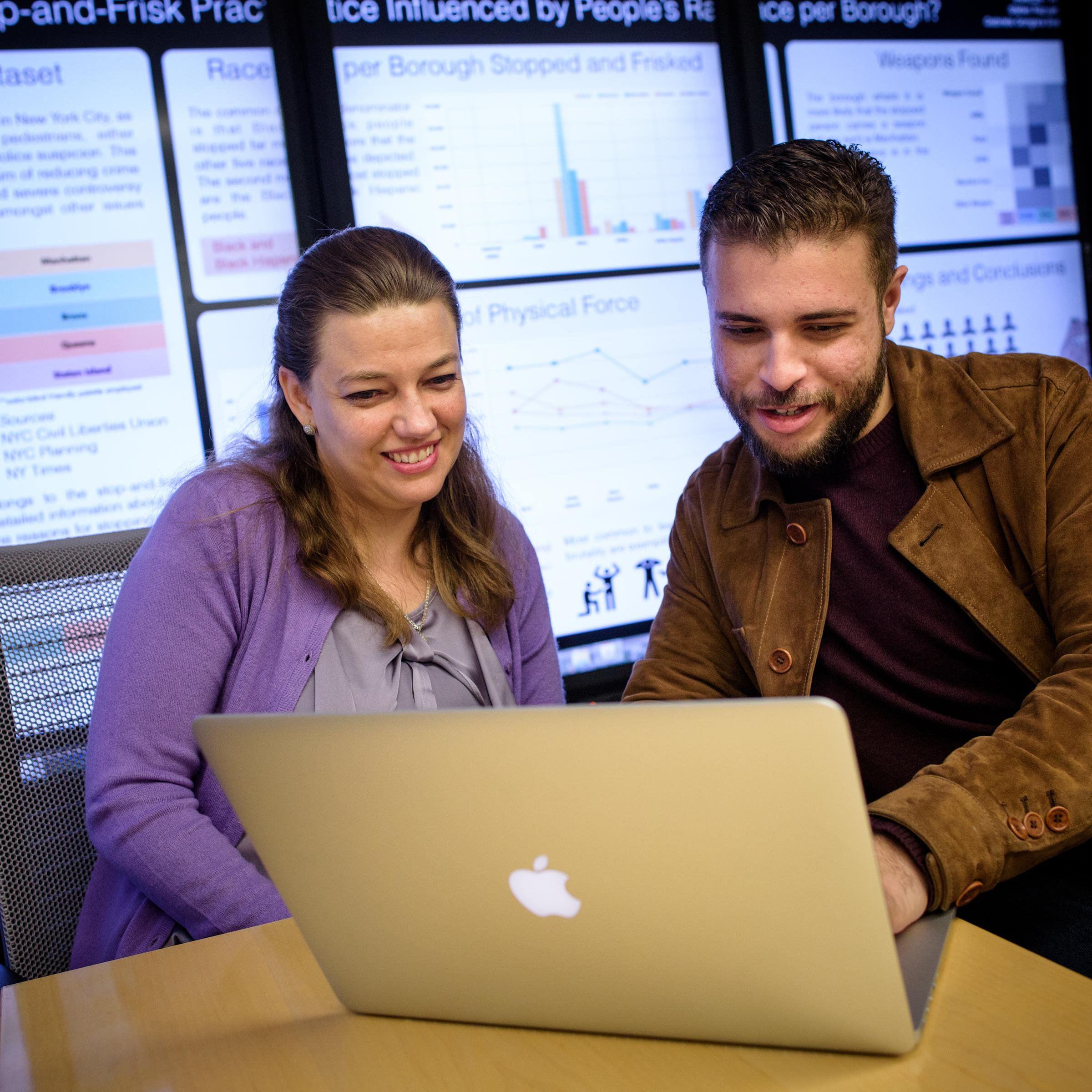 Two students share a laptop.