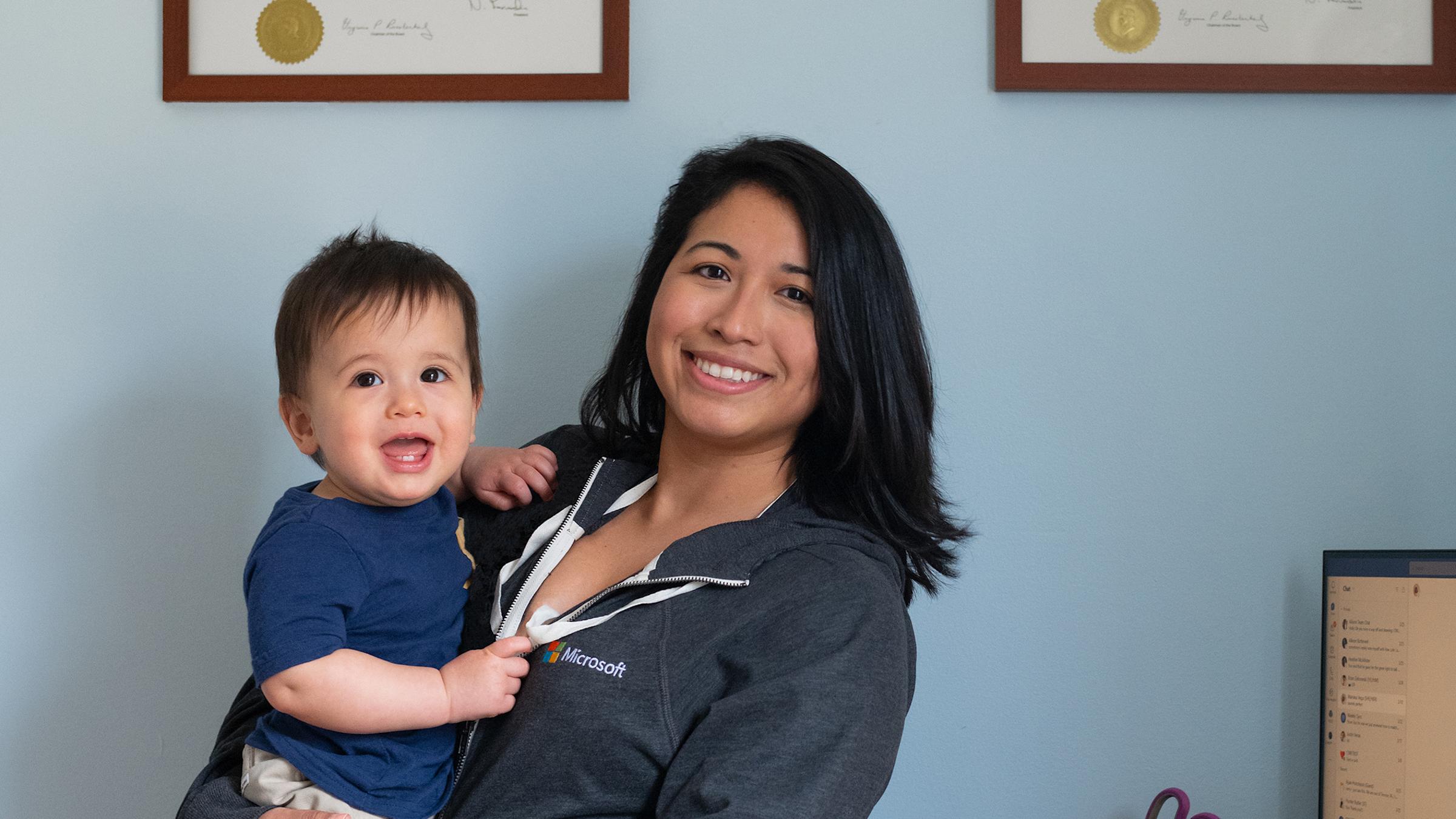 Nathalie Ramos holding her smiling baby in her office.