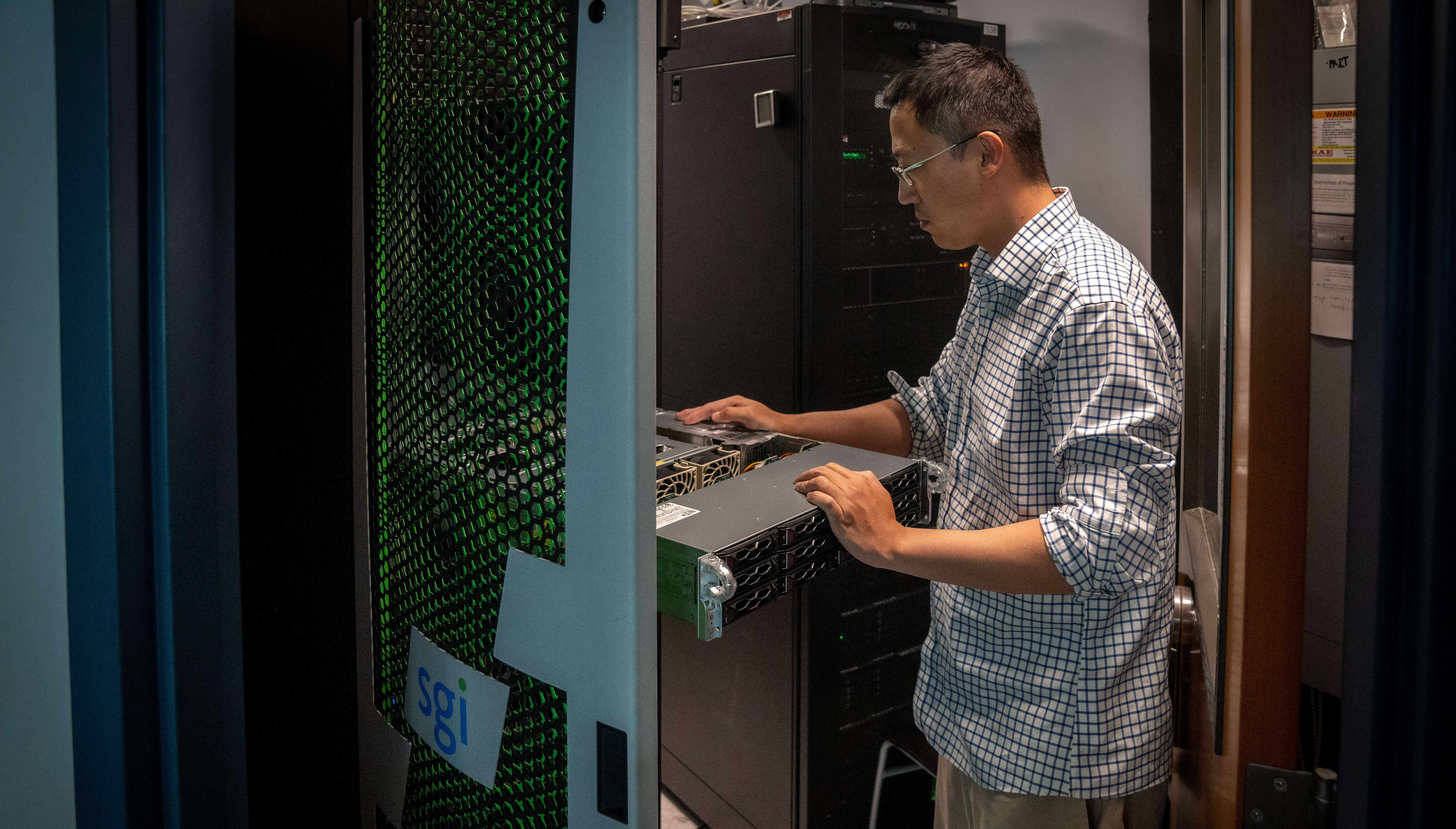 Systems Administrator Zheng Xing examines new Nvidia H100 GPU server from Supermicro 