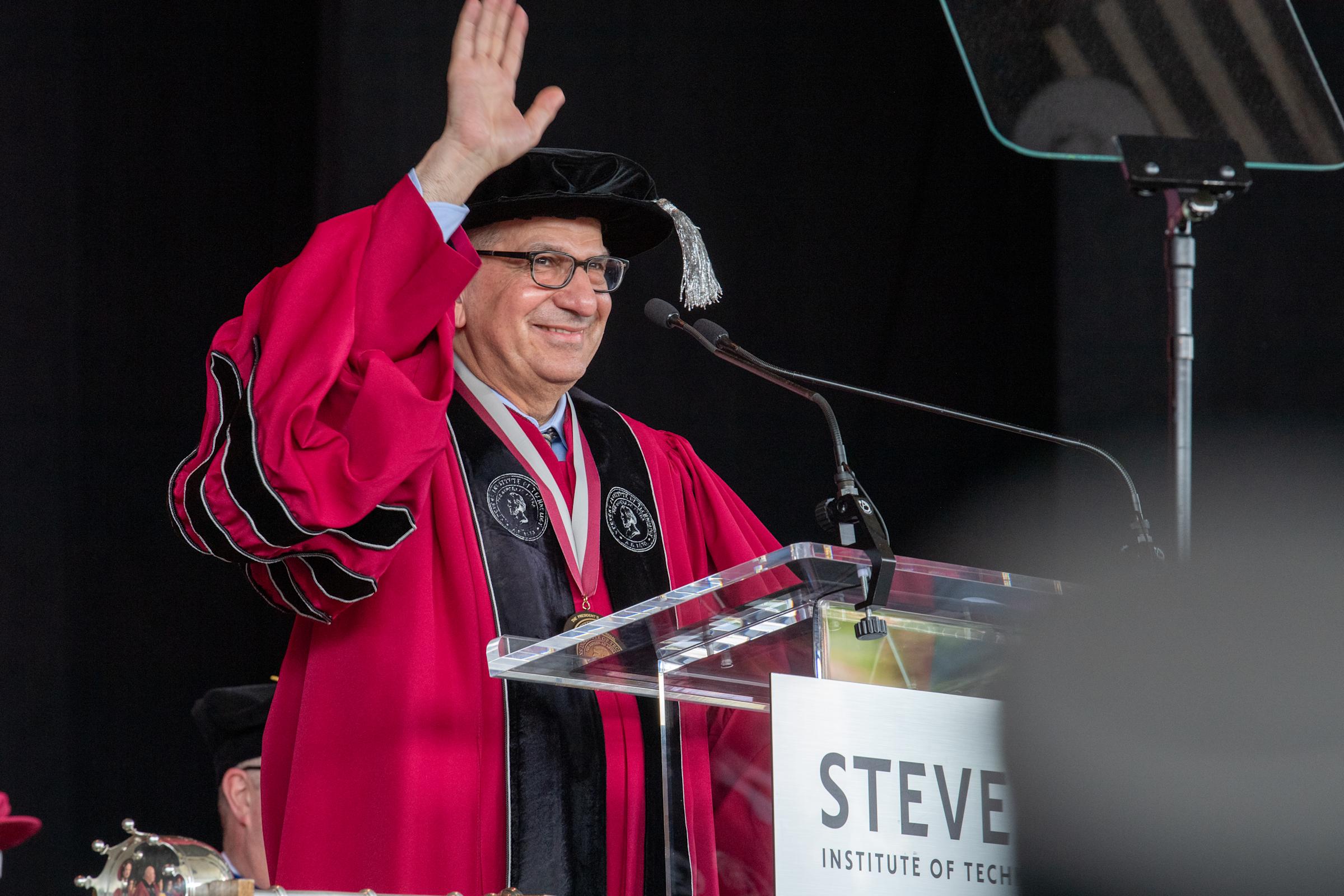 A man in commencement regalia at a podium