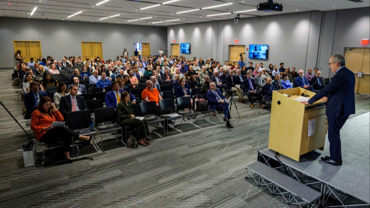 A man standing at a podium speaking to a seated audience.