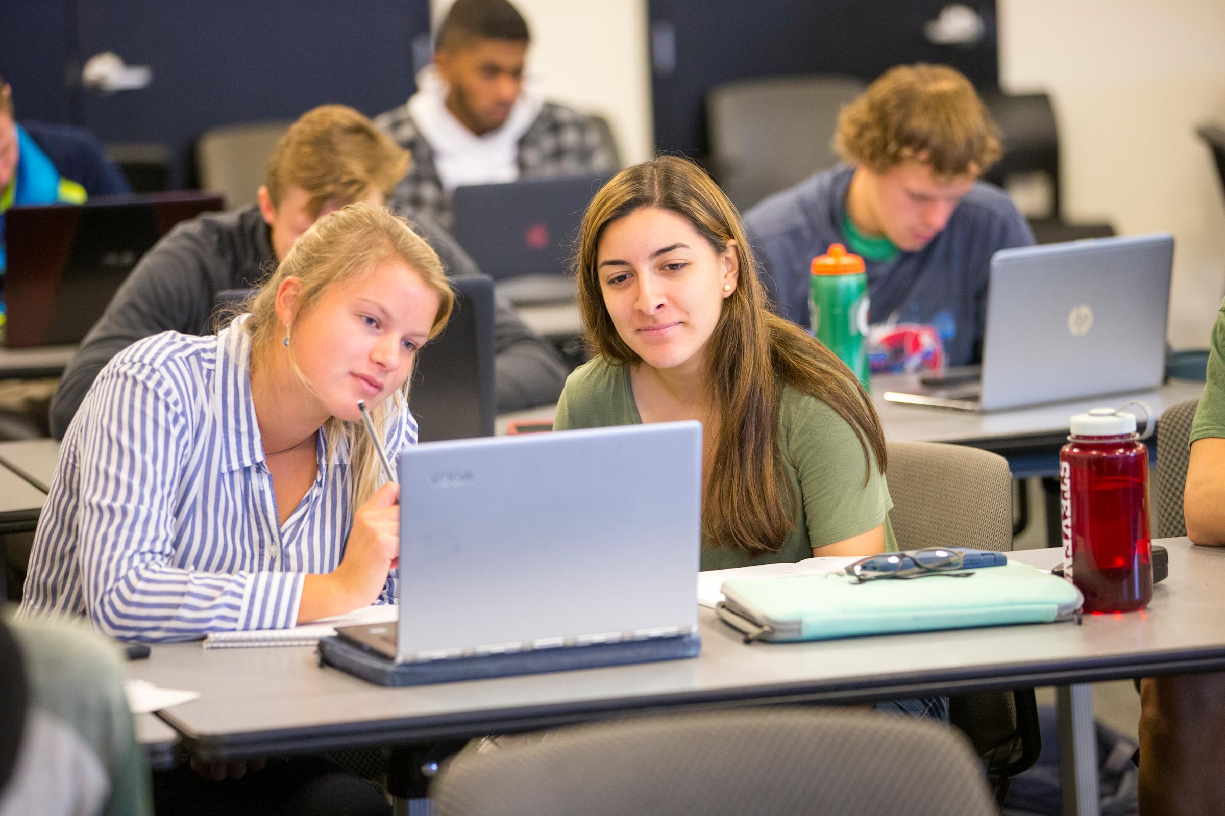 Two students looking at a laptop screen.