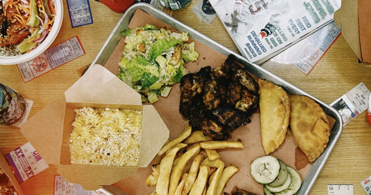 An arm holds up two wraps in front of GTK storefront