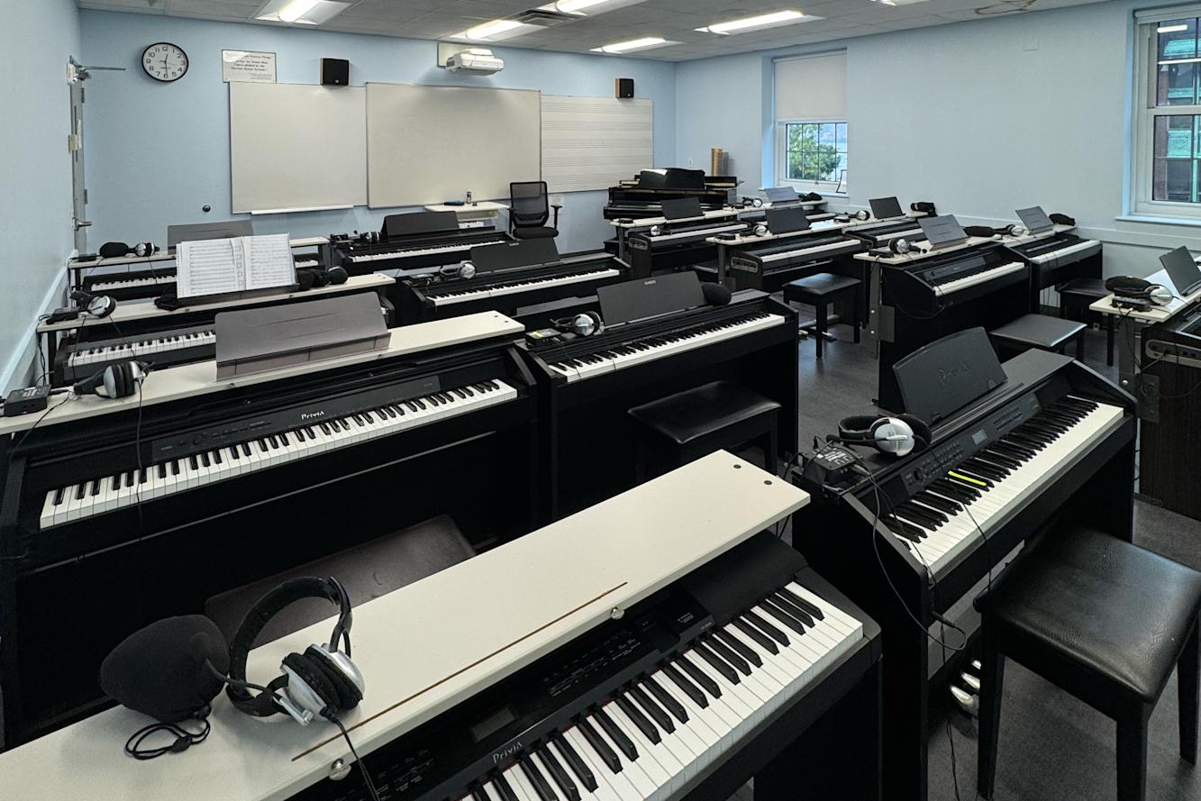 Classroom filled with musical keyboards and a whiteboard in front.