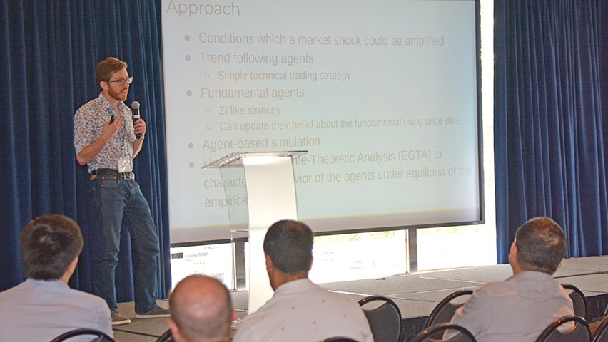 A male presenter delivers a talk at a podium in a conference space at the Stevens campus.