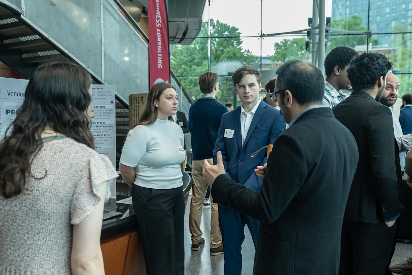 Three students present their project to an onlooker.