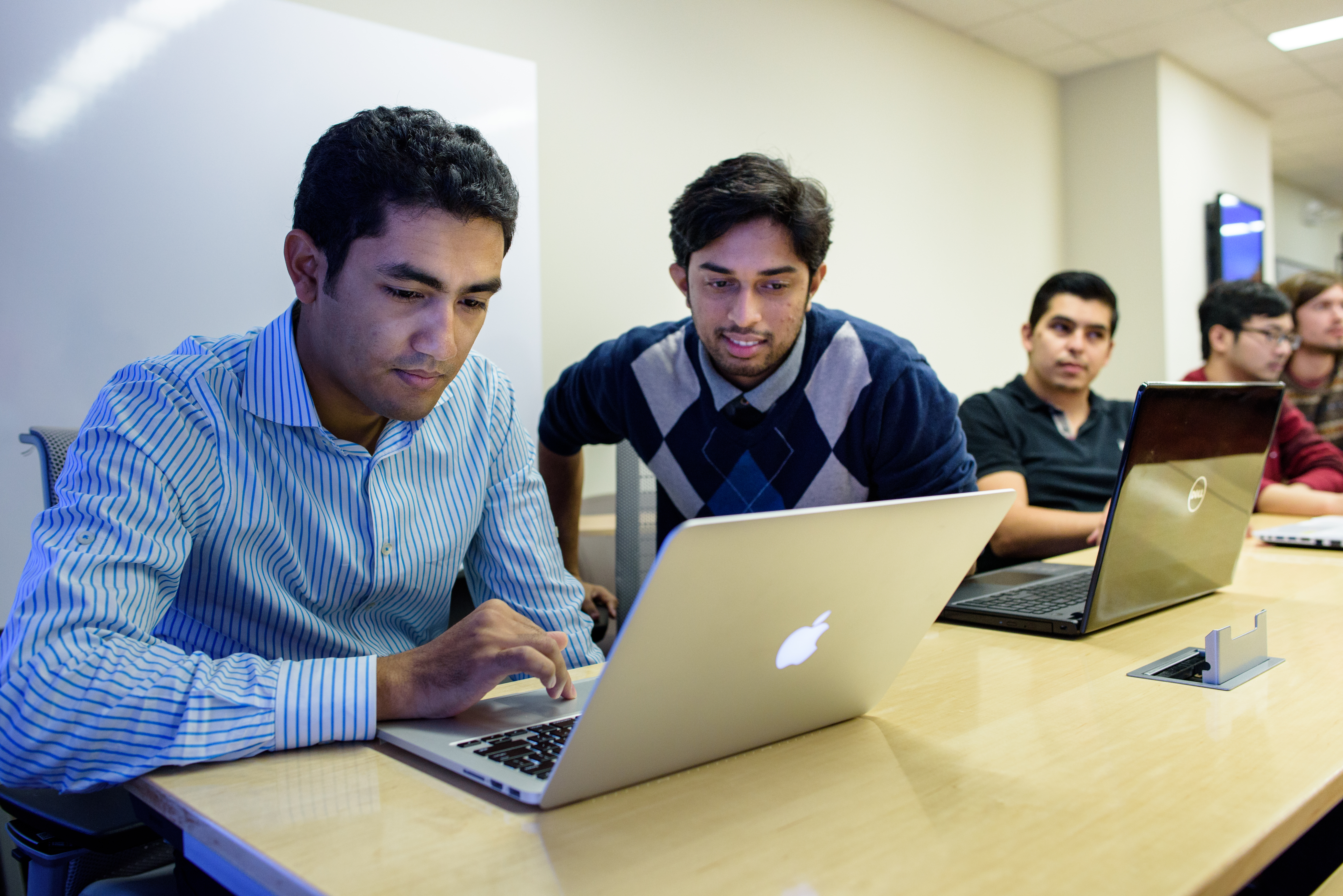 Five students present a project to their professor on a screen