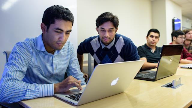 Five students present a project to their professor on a screen