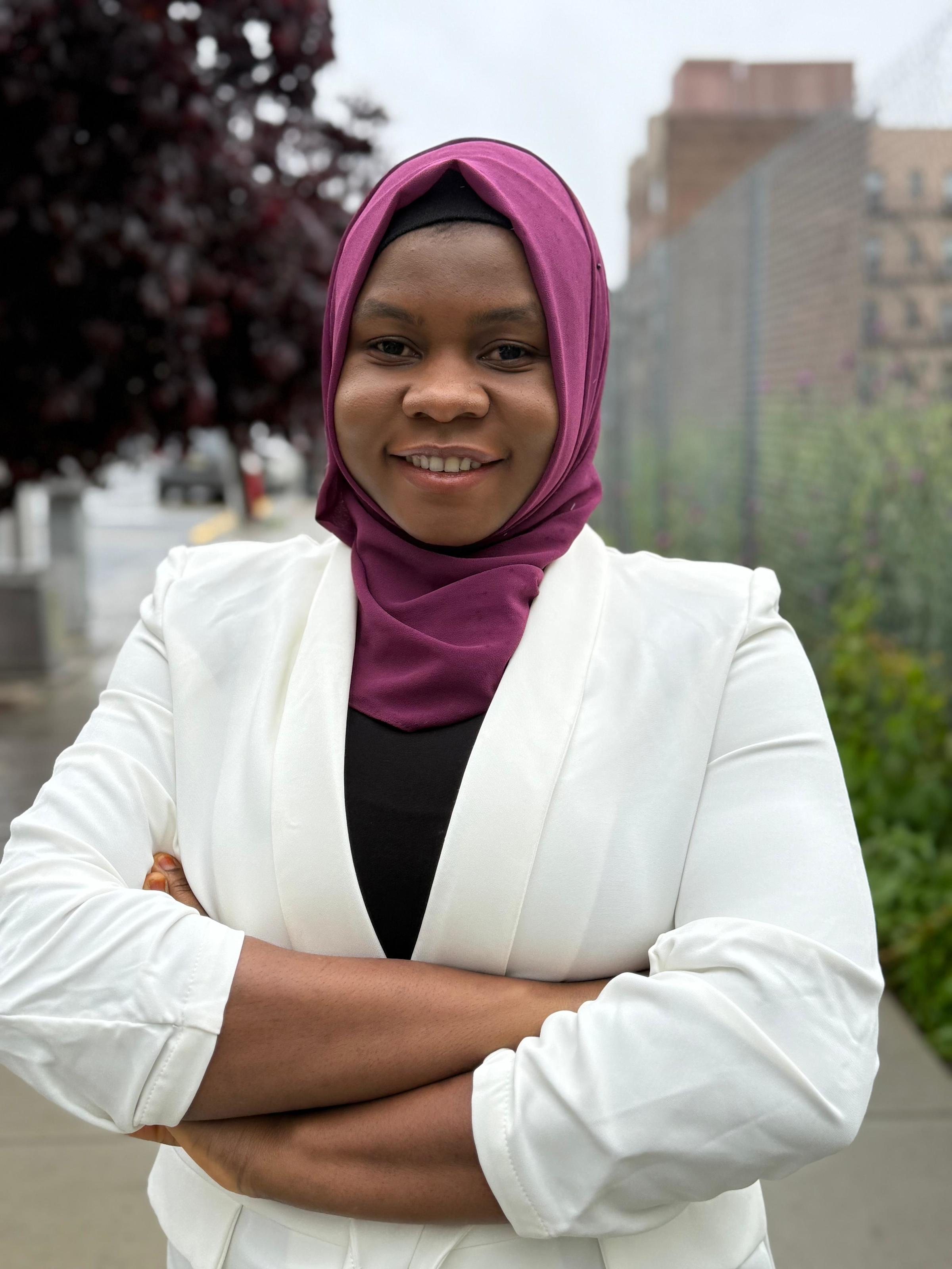 A professional headshot of Ph..D. student Lateefat Kalejaye, standing with her arms folded outdoors.