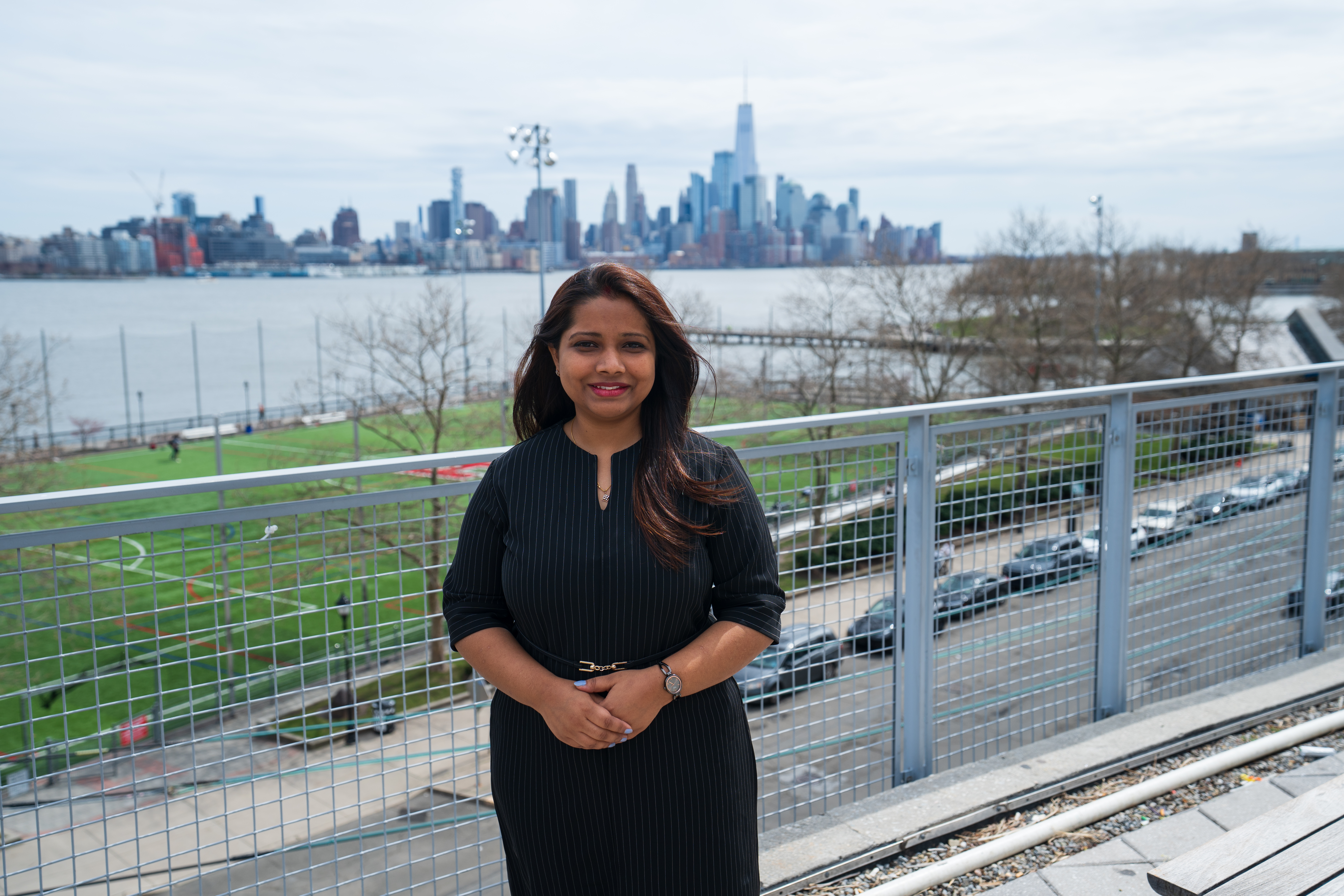 Diksha stands on the Babbio patio with NYC skyline in the background.