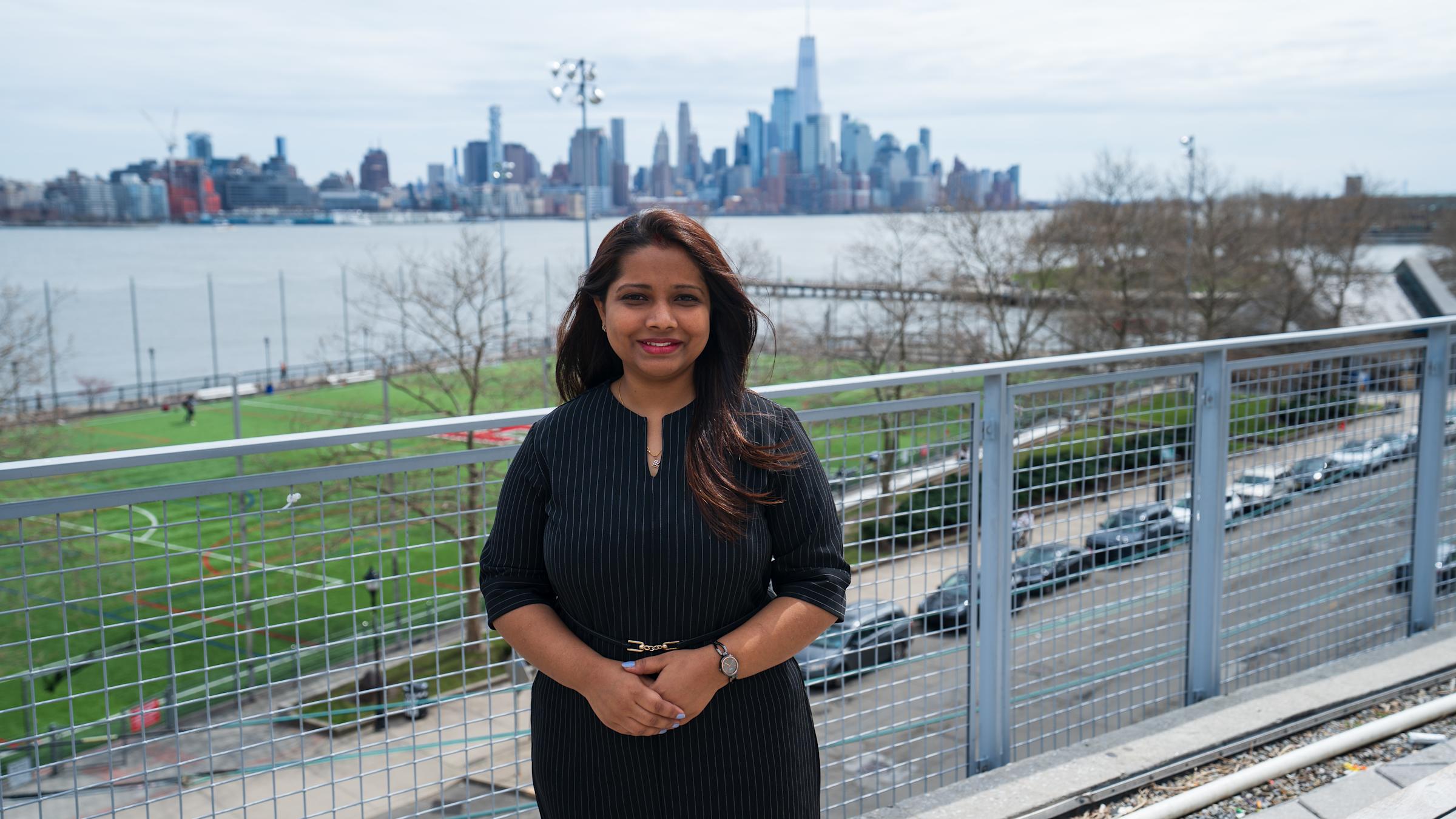 Diksha stands on the Babbio patio with NYC skyline in the background.